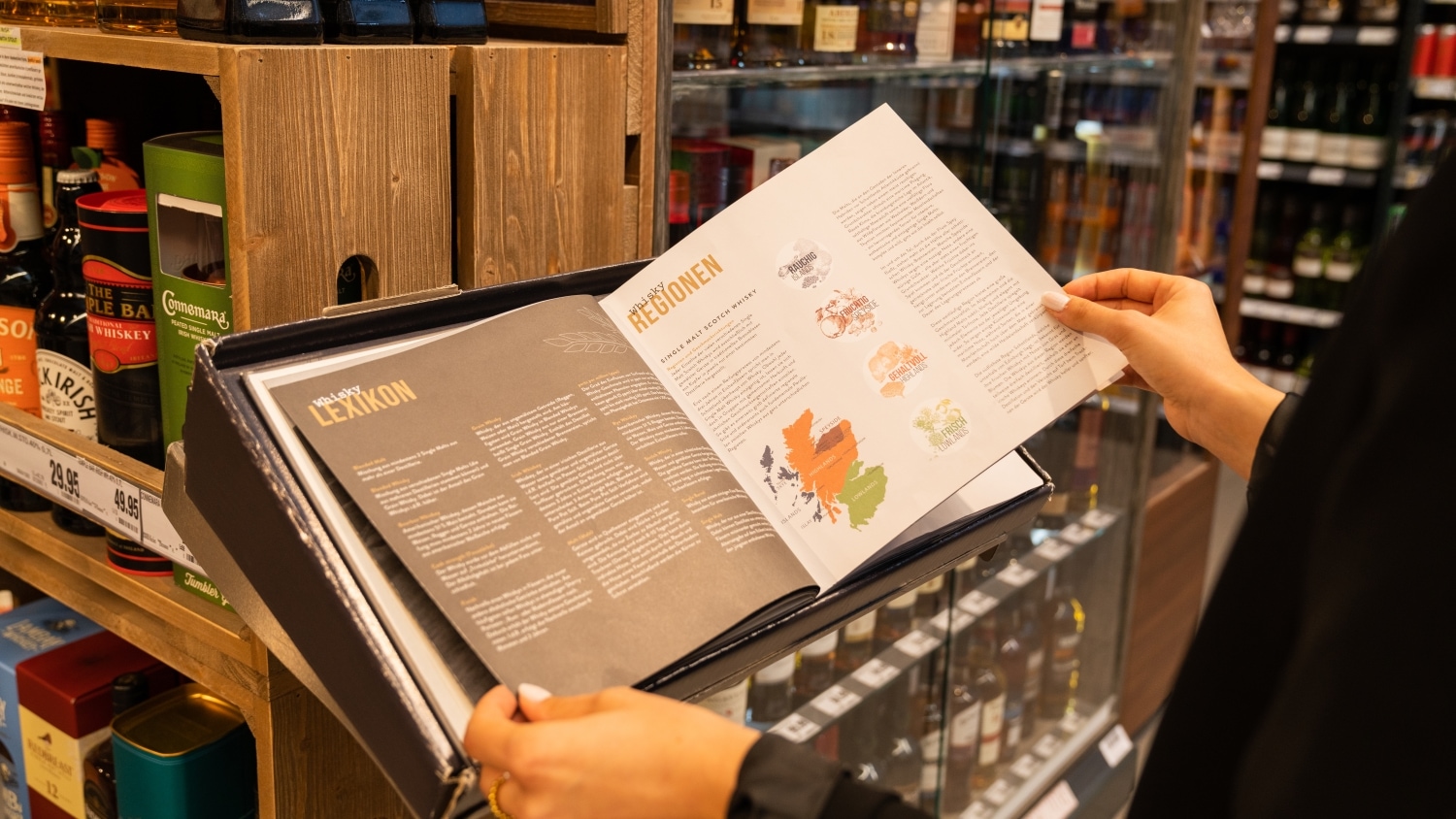 Blick über die Schulter einer Frau die durch ein Whisky-Lexikon blättert.