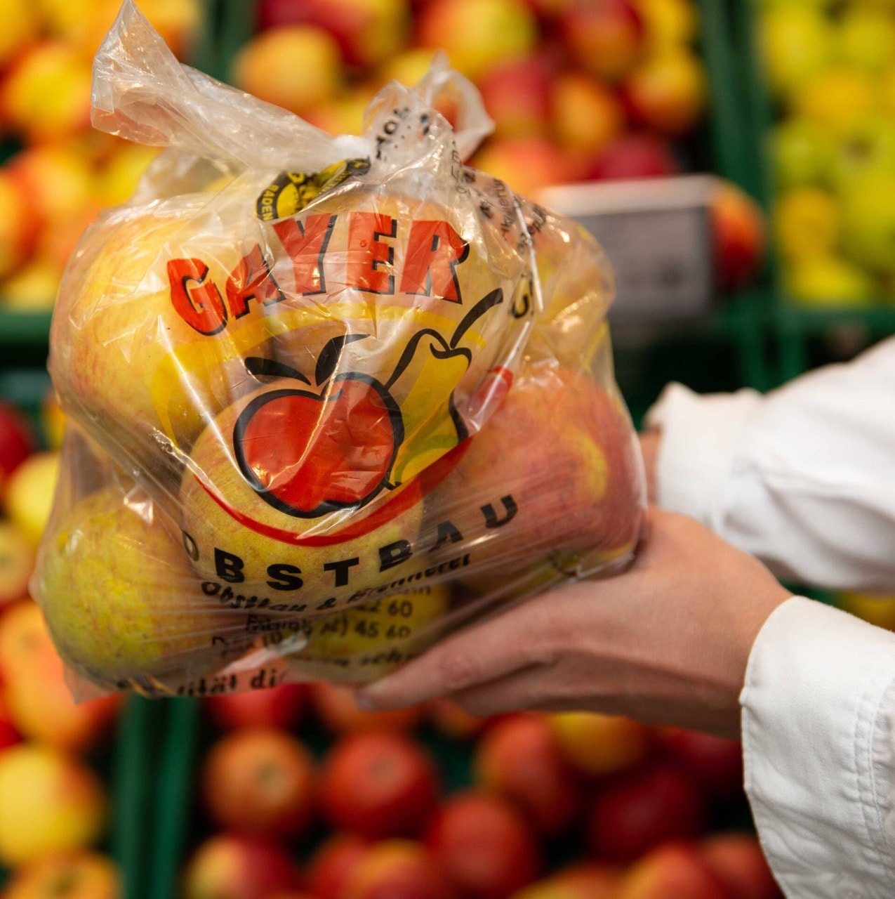 Zwei Hände halten eine Tüte mit Äpfeln.