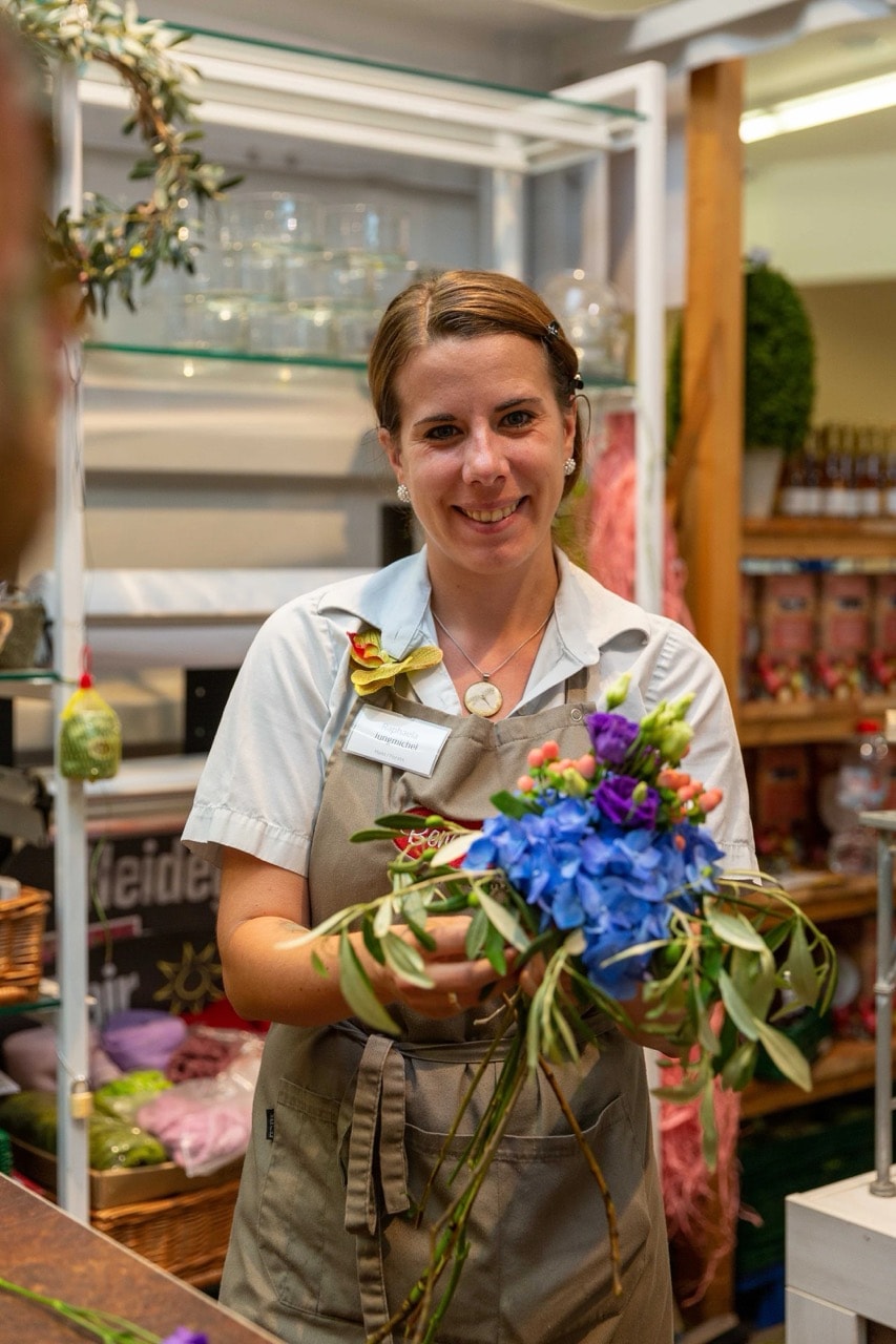 Eine lächelnde Mitarbeiterin hält einen Blumenstrauß in den Händen.