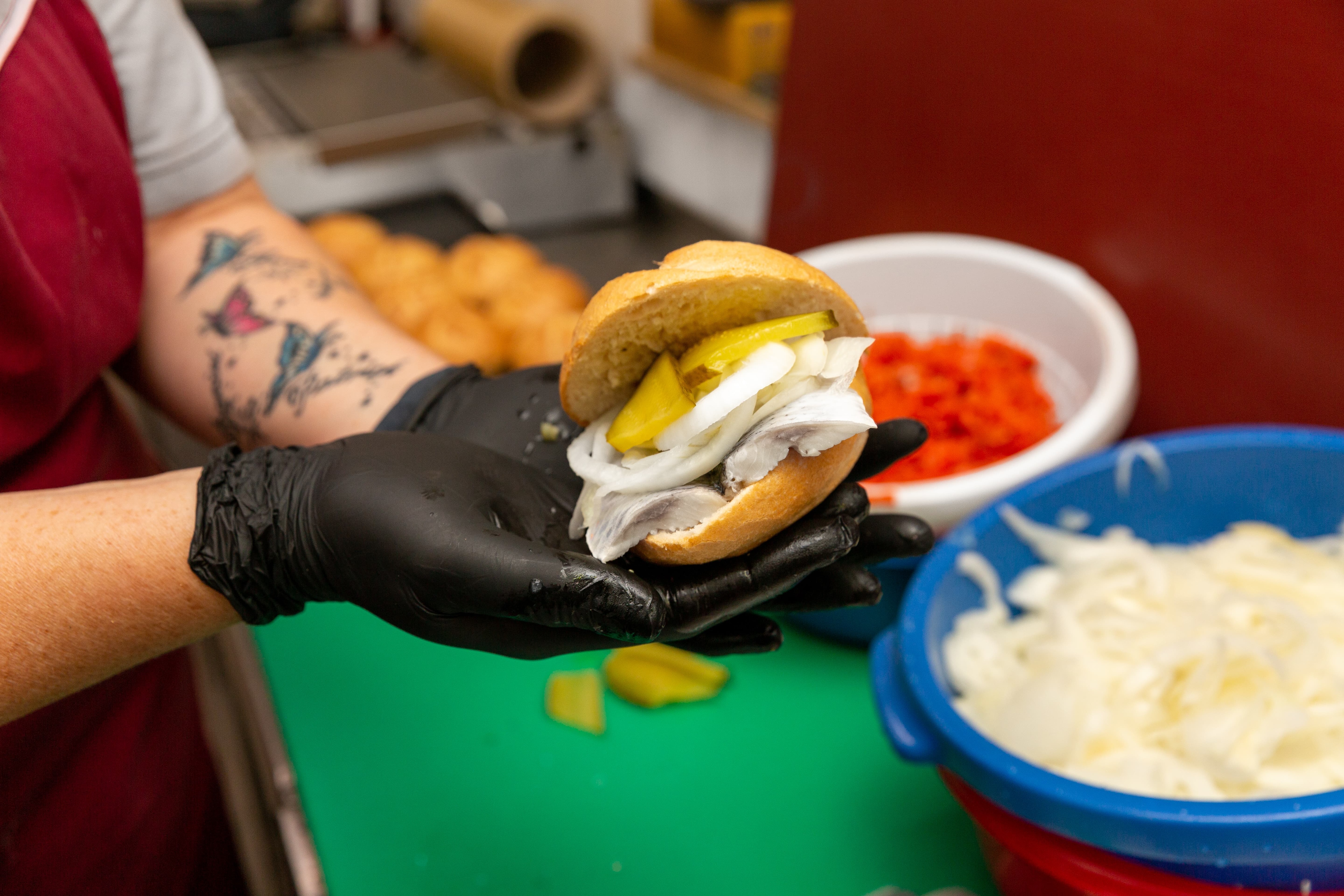 Zwei Hände halten ein frischbelegtes Fischbrötchen.