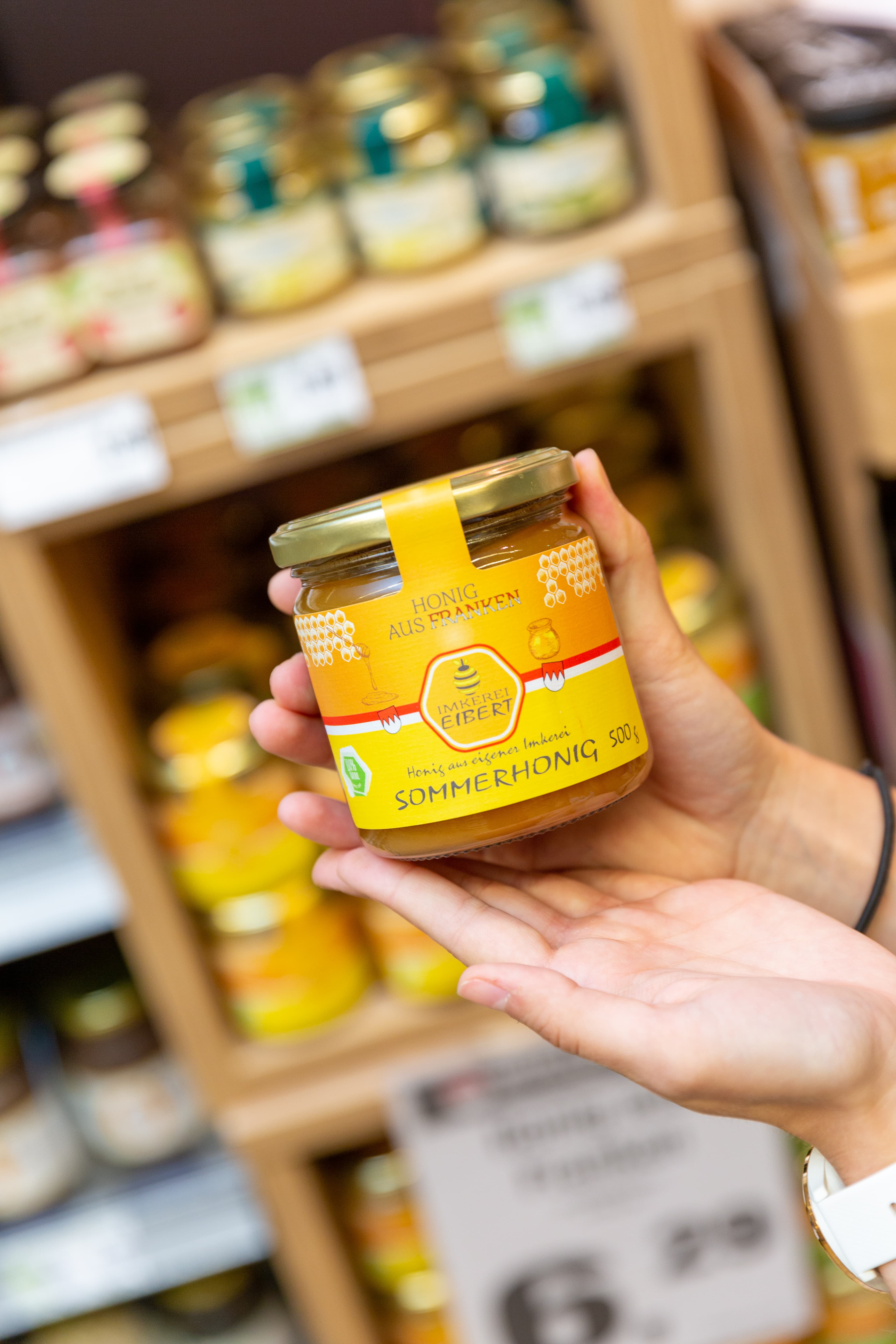 Zwei Hände halten ein Glas Honig aus Franken.