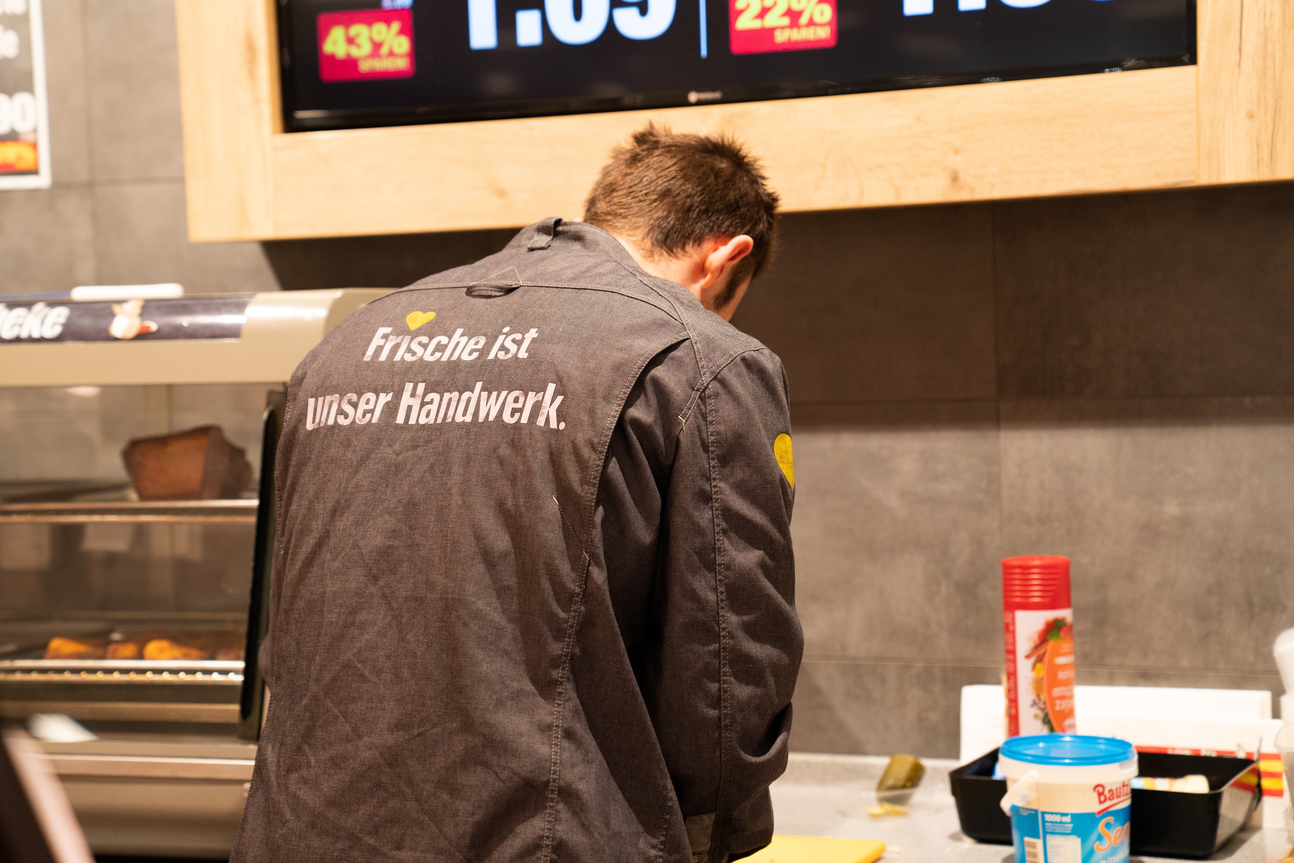 Auf der Rückseite des Hemdes eines Mitarbeiters steht: Frische ist unser Handwerk.