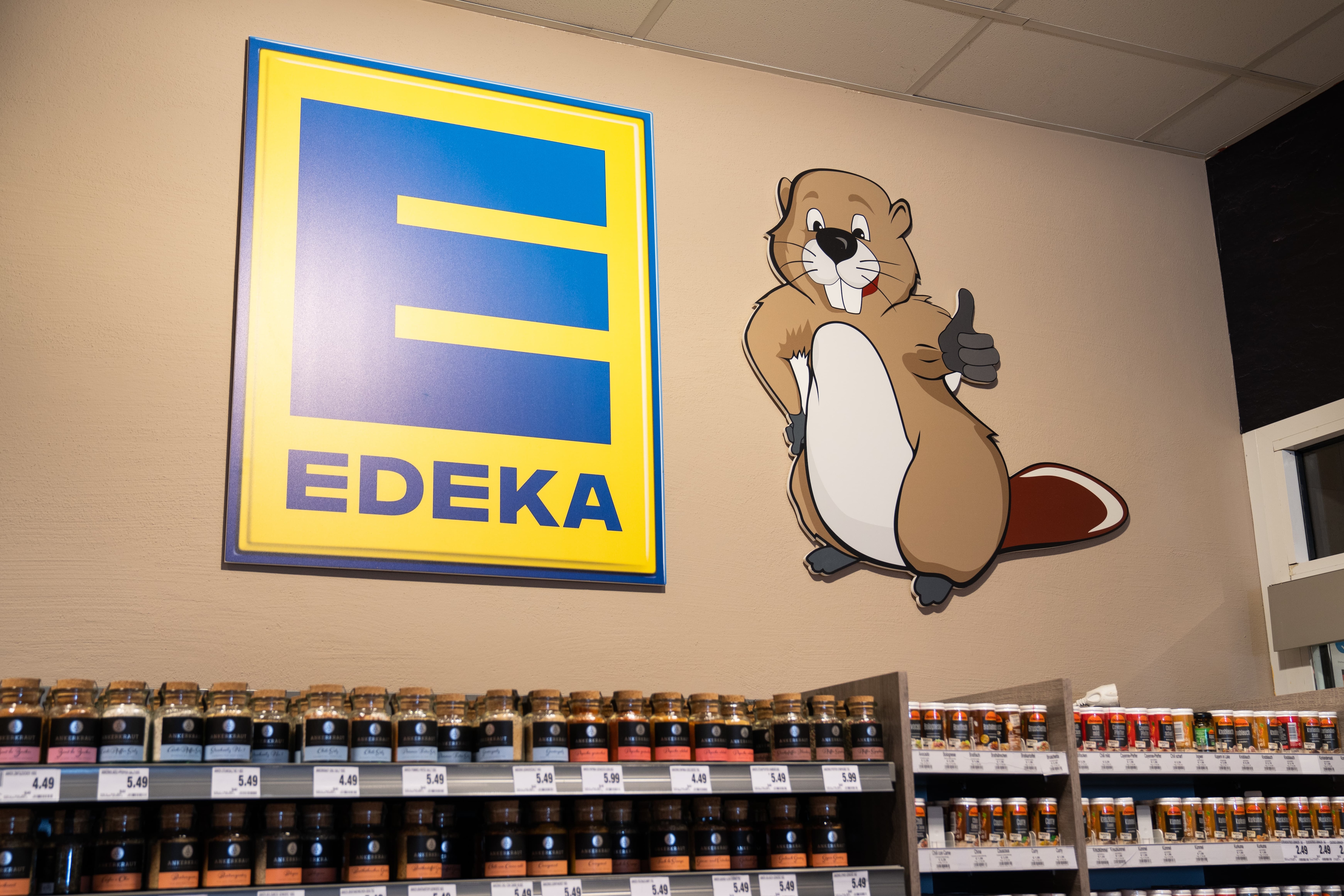 Über den Gewürzregalen hängt ein großes EDEKA-Logo und ein Biber.