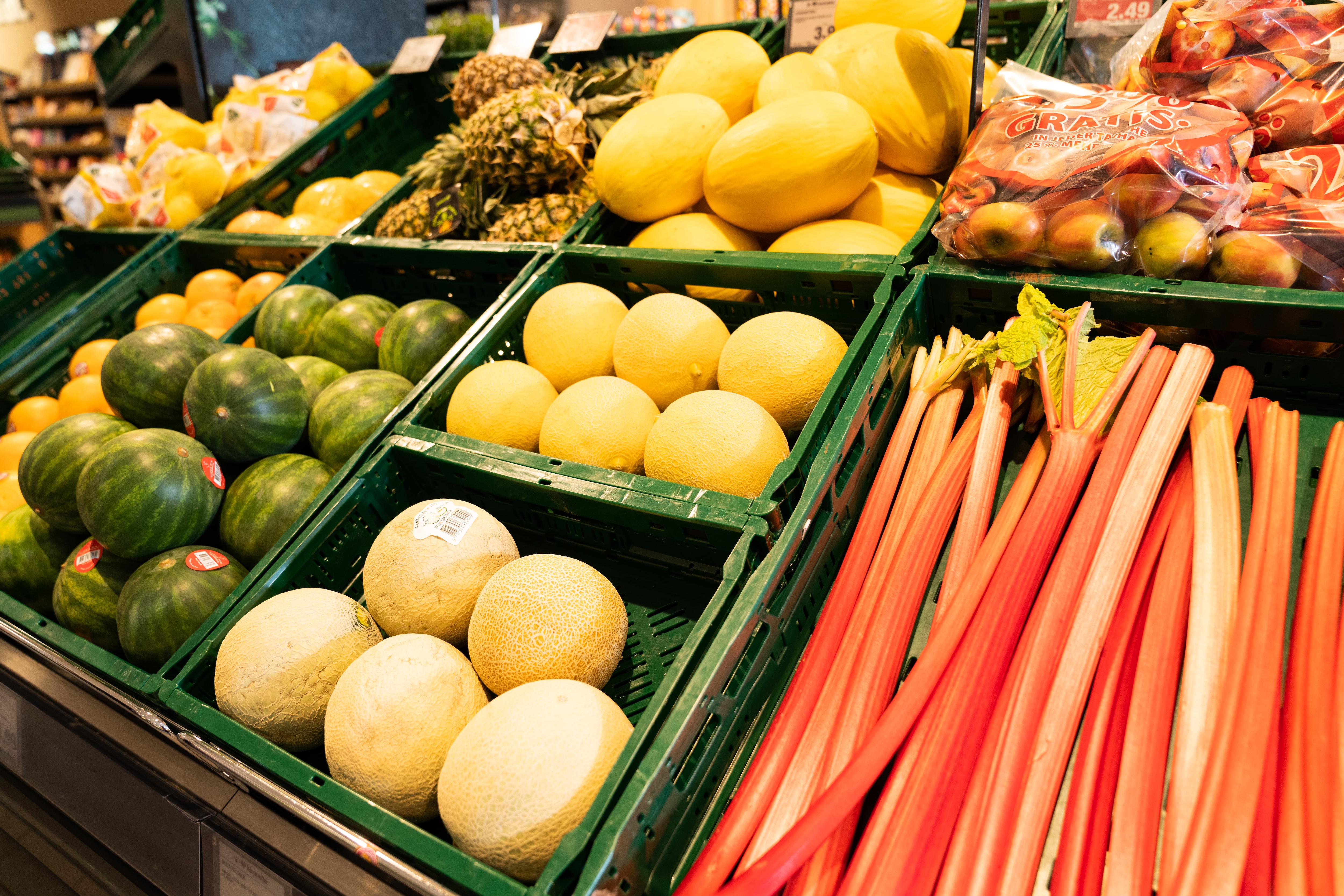 Obstauslage mit Wassermelonen, Honigmelonen, Rhabarber, Ananas und Äpfeln.