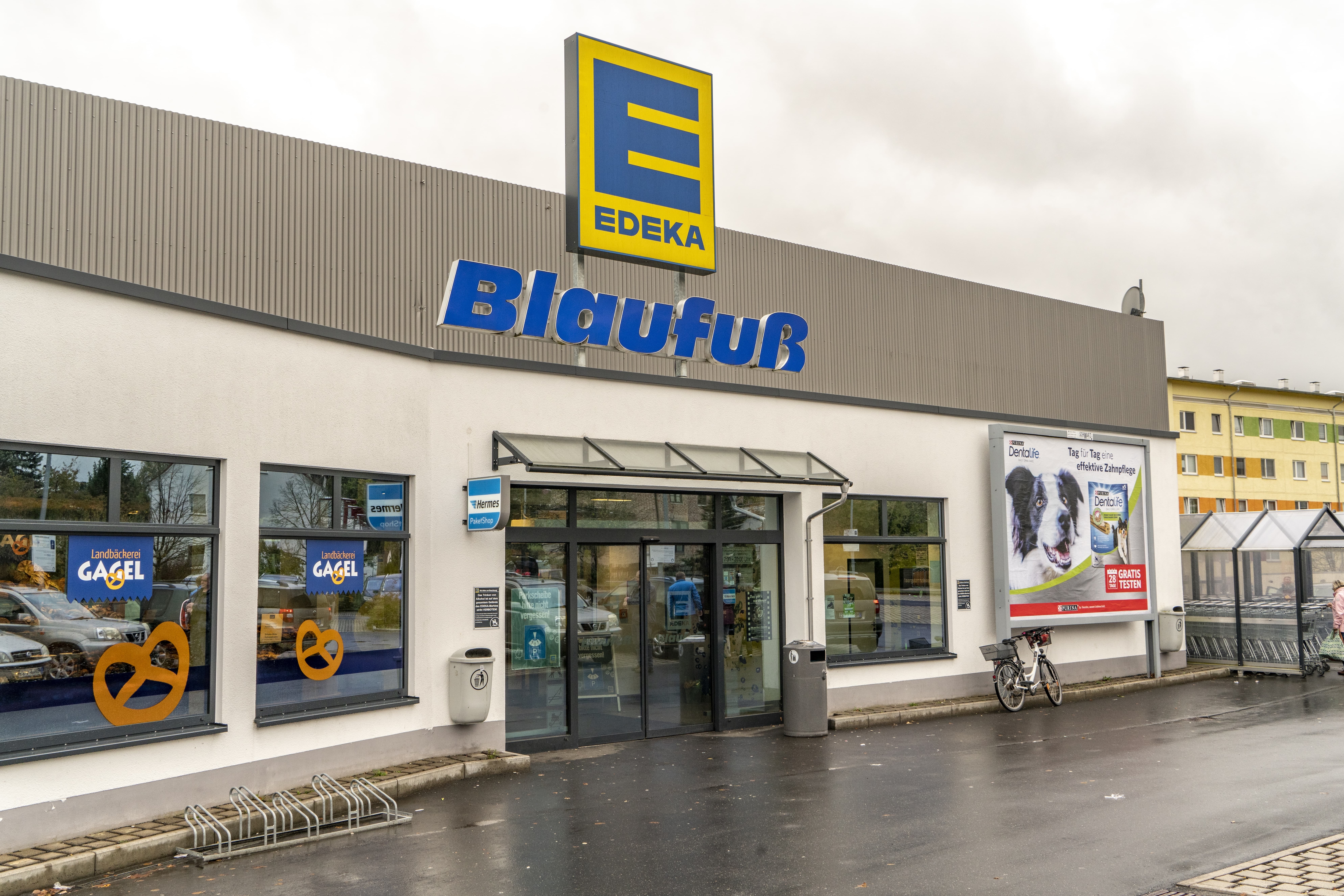 Front des Markts, bei regnerischem Wetter, mit dem Schriftzug EDEKA Blaufuß über dem Eingang.