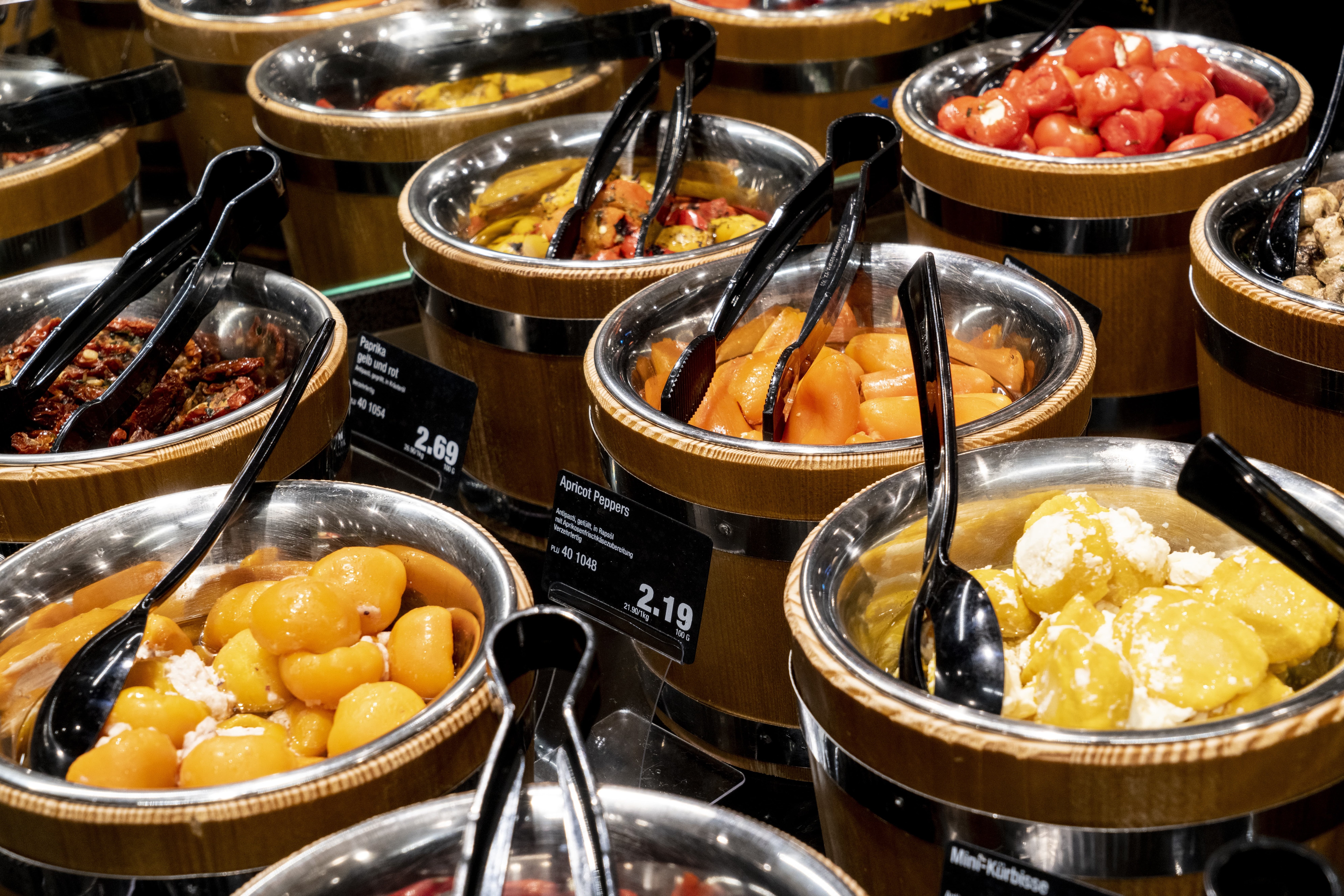 Eine Auswahl an verschiedenen eingelegten Feinkostspezialitäten in der Frischetheke eines Edeka-Marktes.