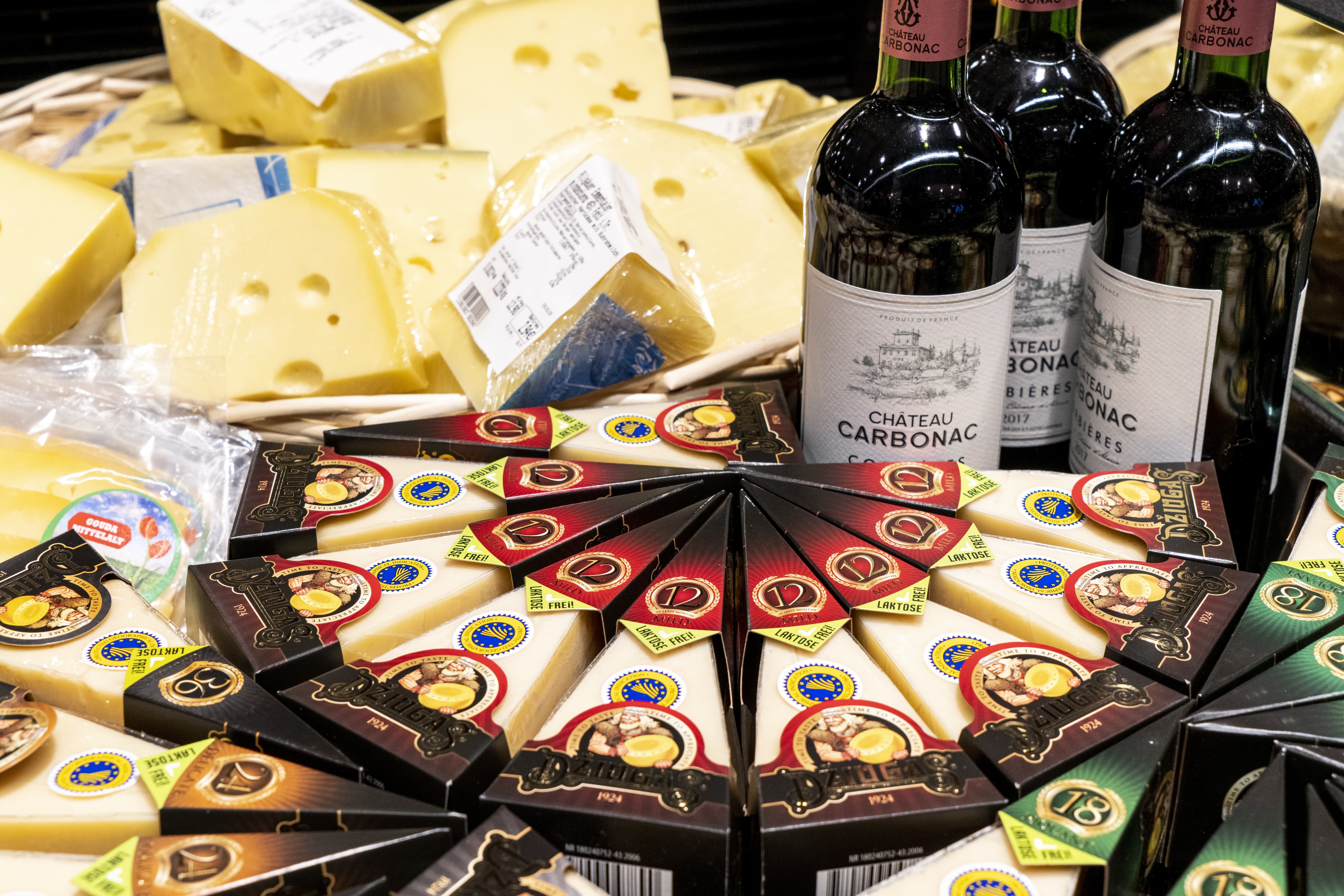 Unterschiedliche Käsesorten und drei Rotweinflaschen.