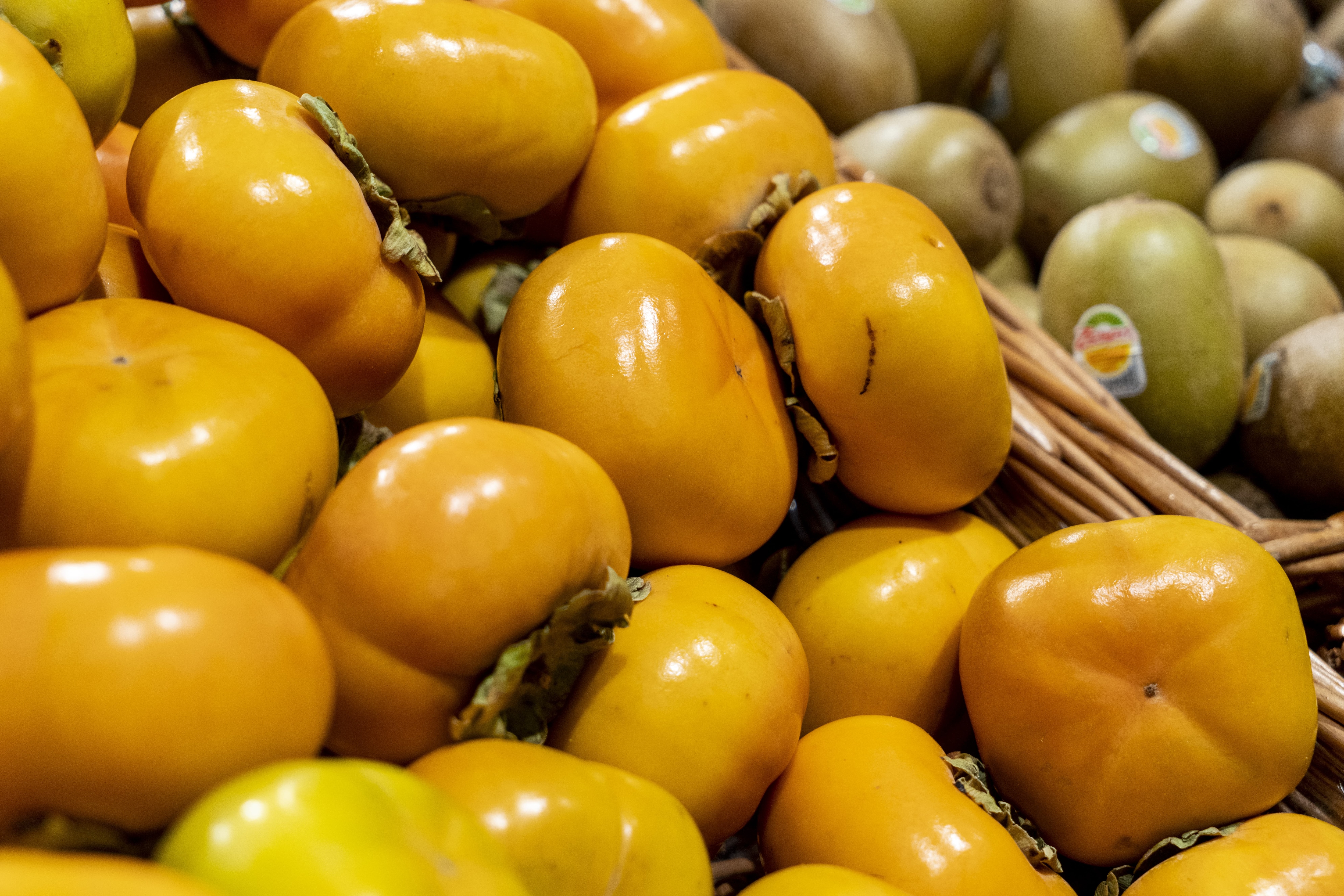 Nahaufnahmen eines Korbes voller Kakis.