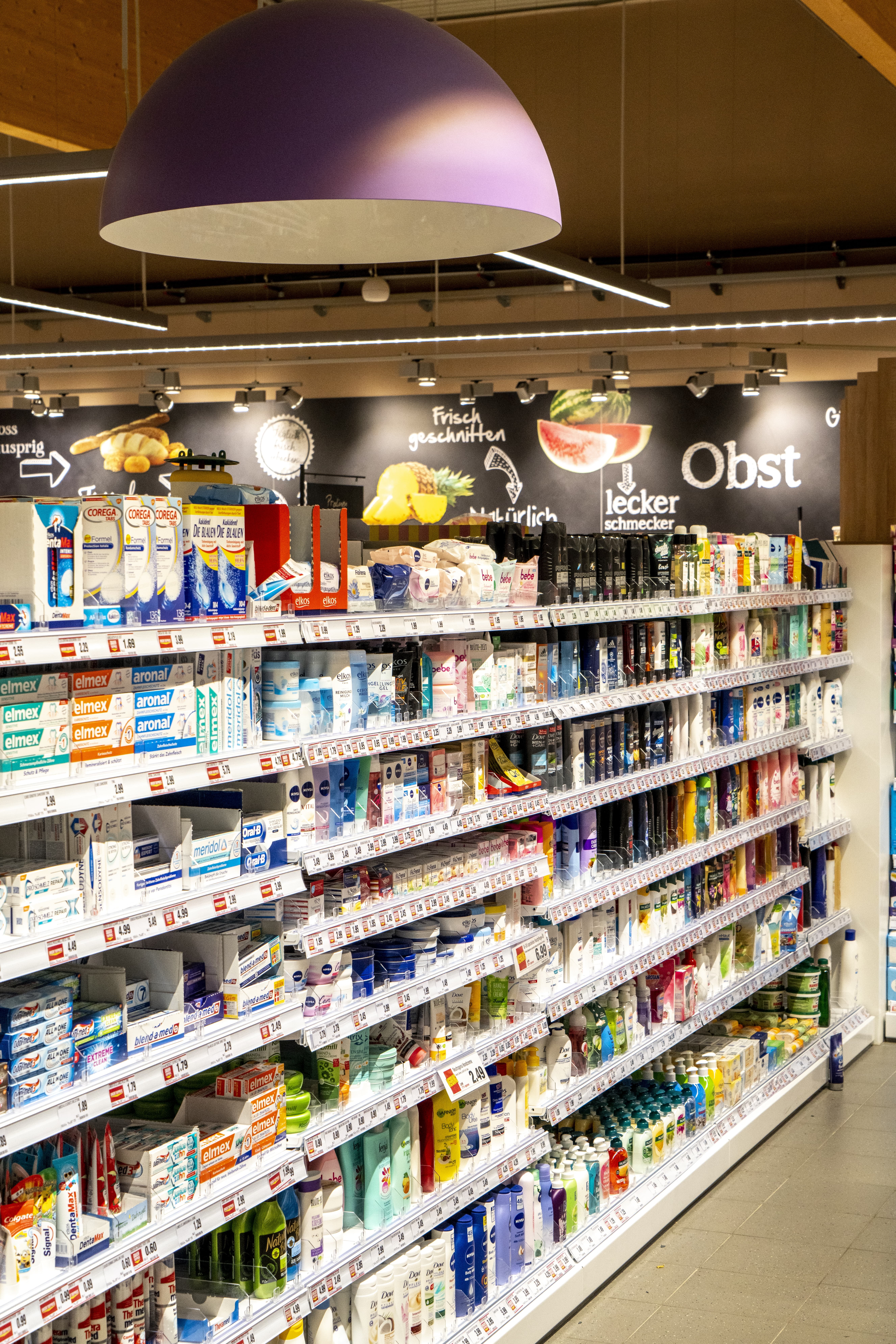 Die Drogerieabteilung eines EDEKA-Markts, mit großen Hängelampen darüber.