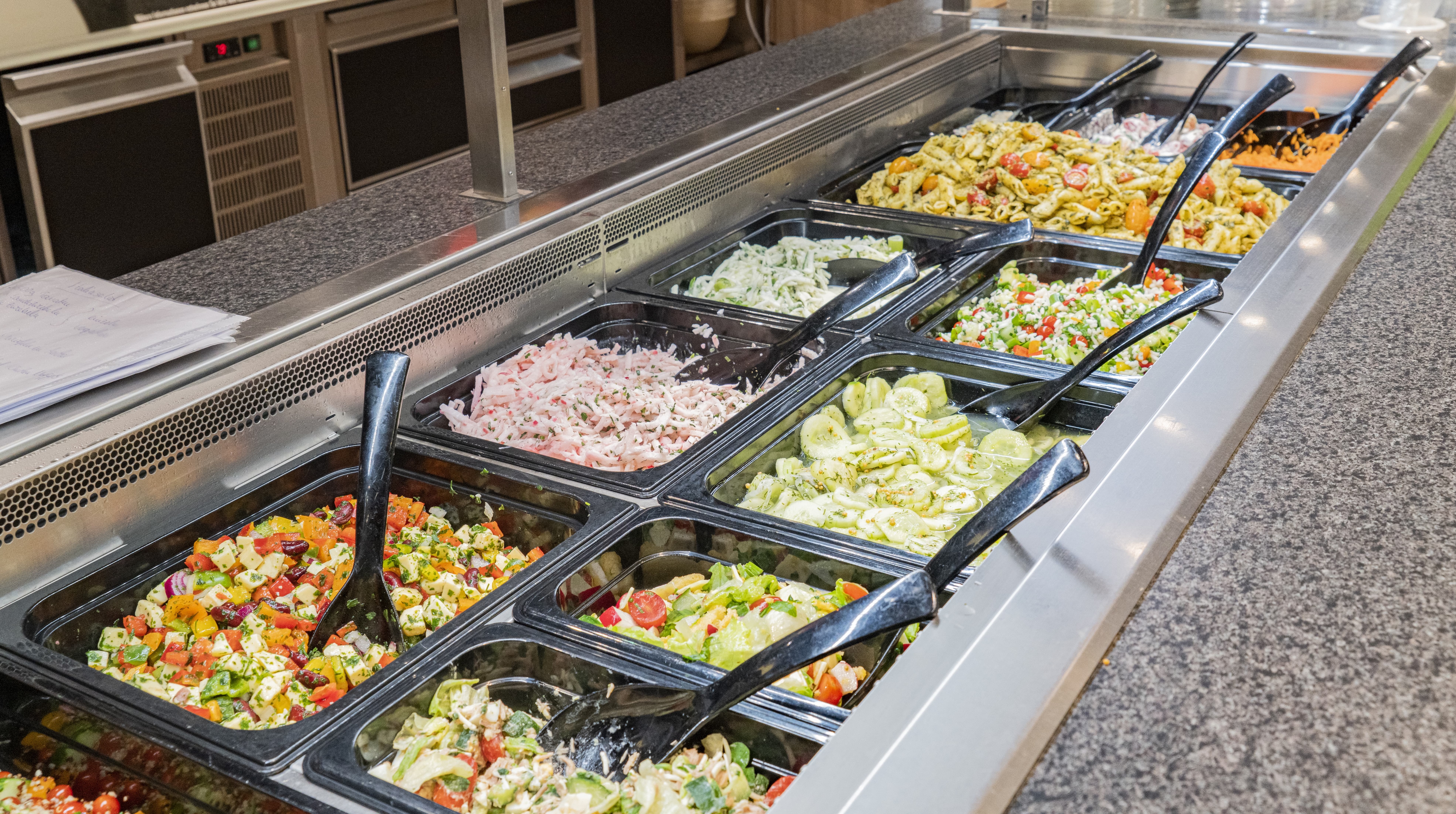 Die Salatbar in einem EDEKA-Markt, reich bestückt mit Nudelsalat, Gurkensalat und anderen.