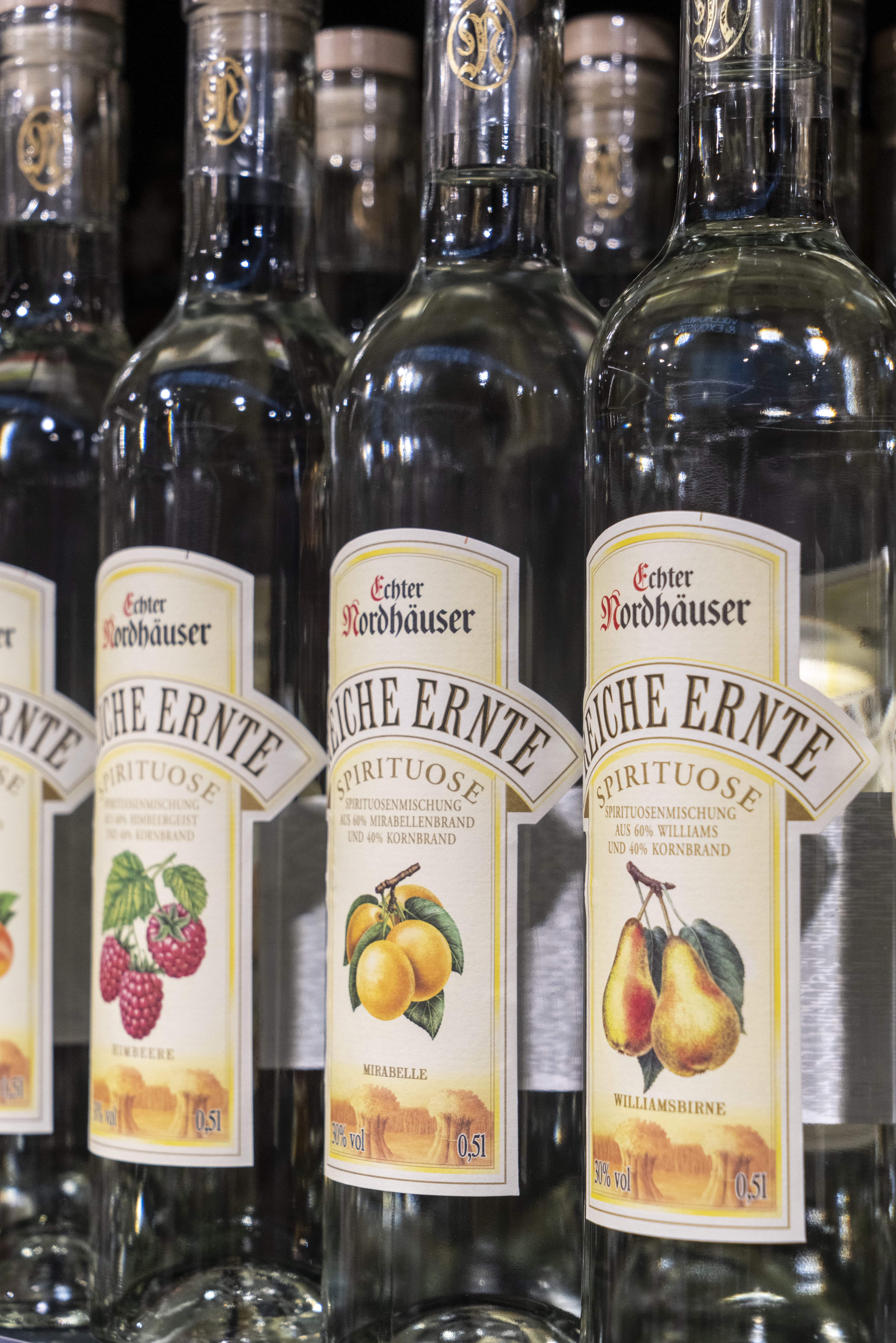 Vier Flaschen mit einer regionalen Spirituose, auf dem Etikett sind Früchte abgedruckt.