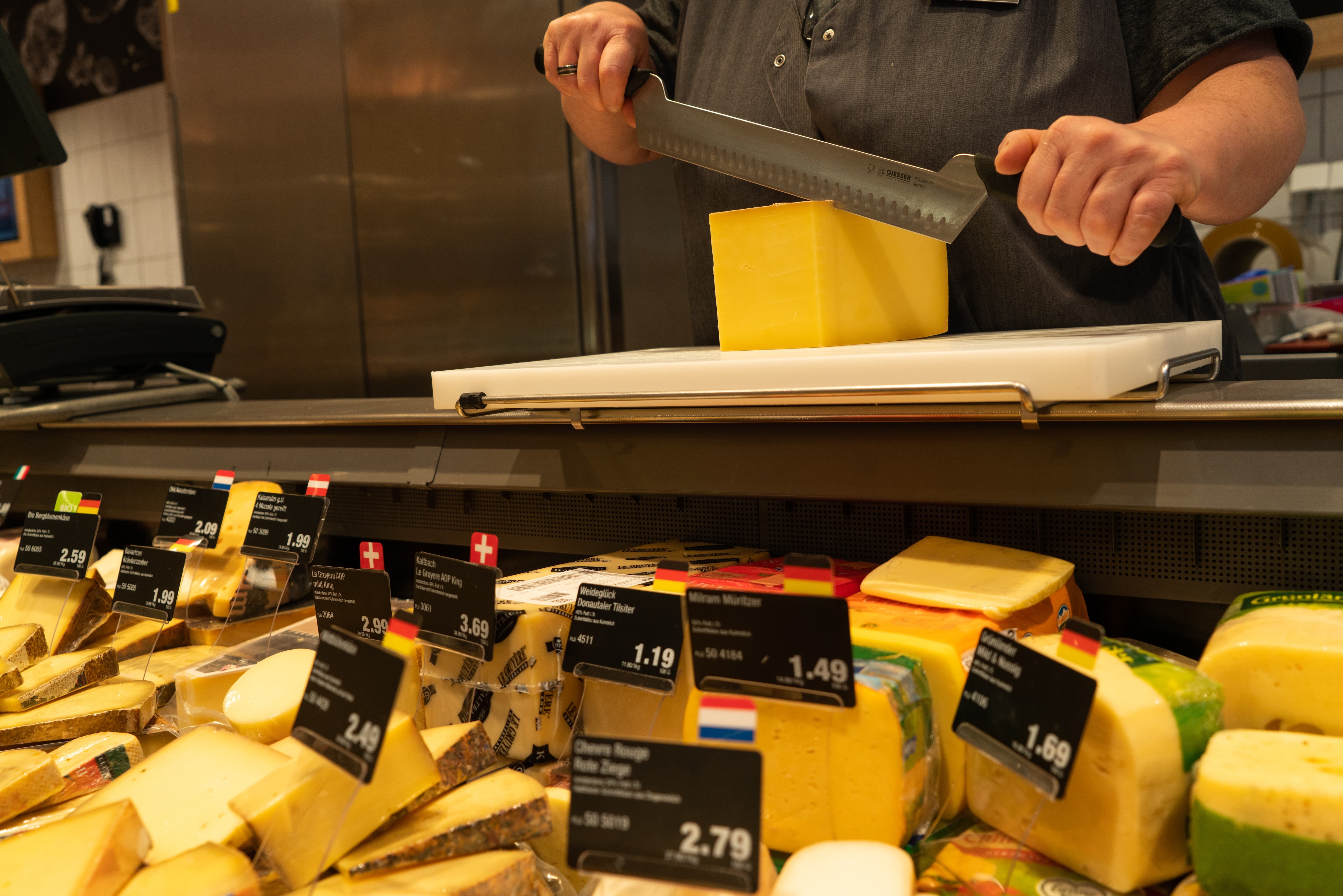 Eine Mitarbeiterin schneidet Käse an der Frischetheke eines Edeka-Marktes.
