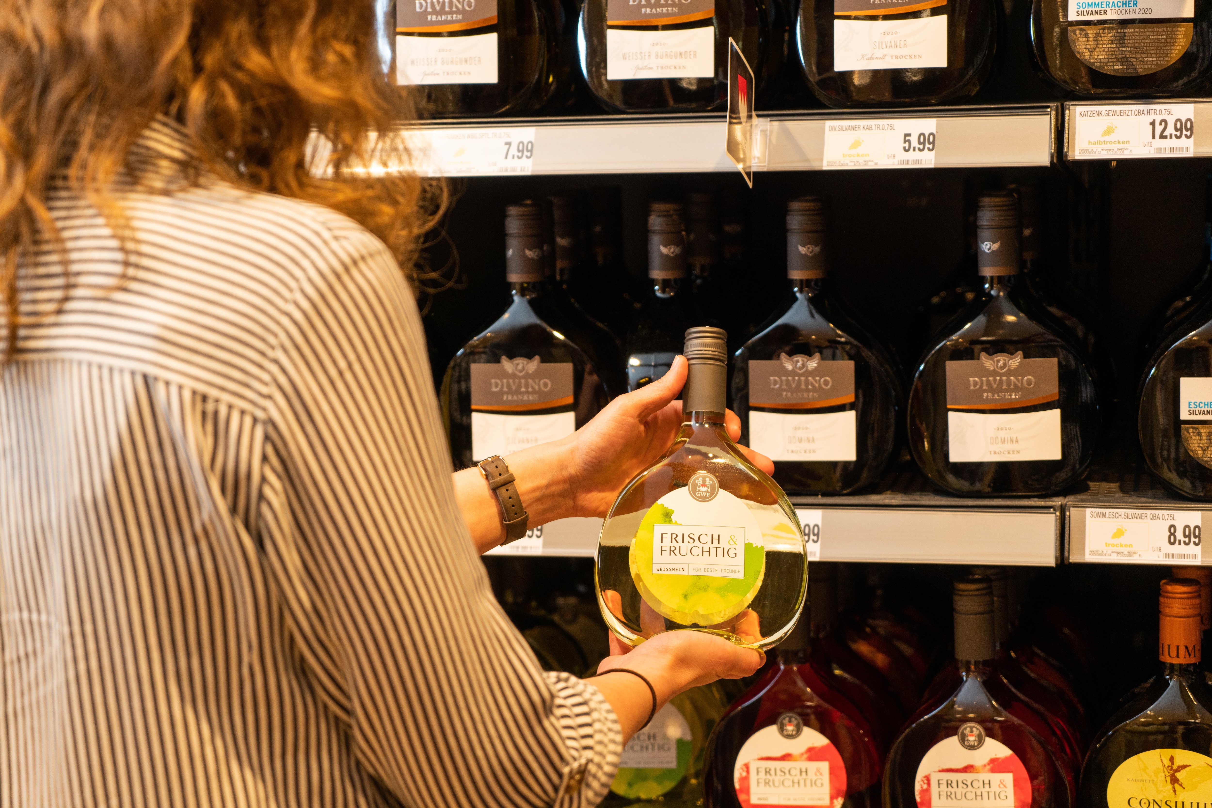 Eine Frau hält eine Flasche Wein in den Händen.