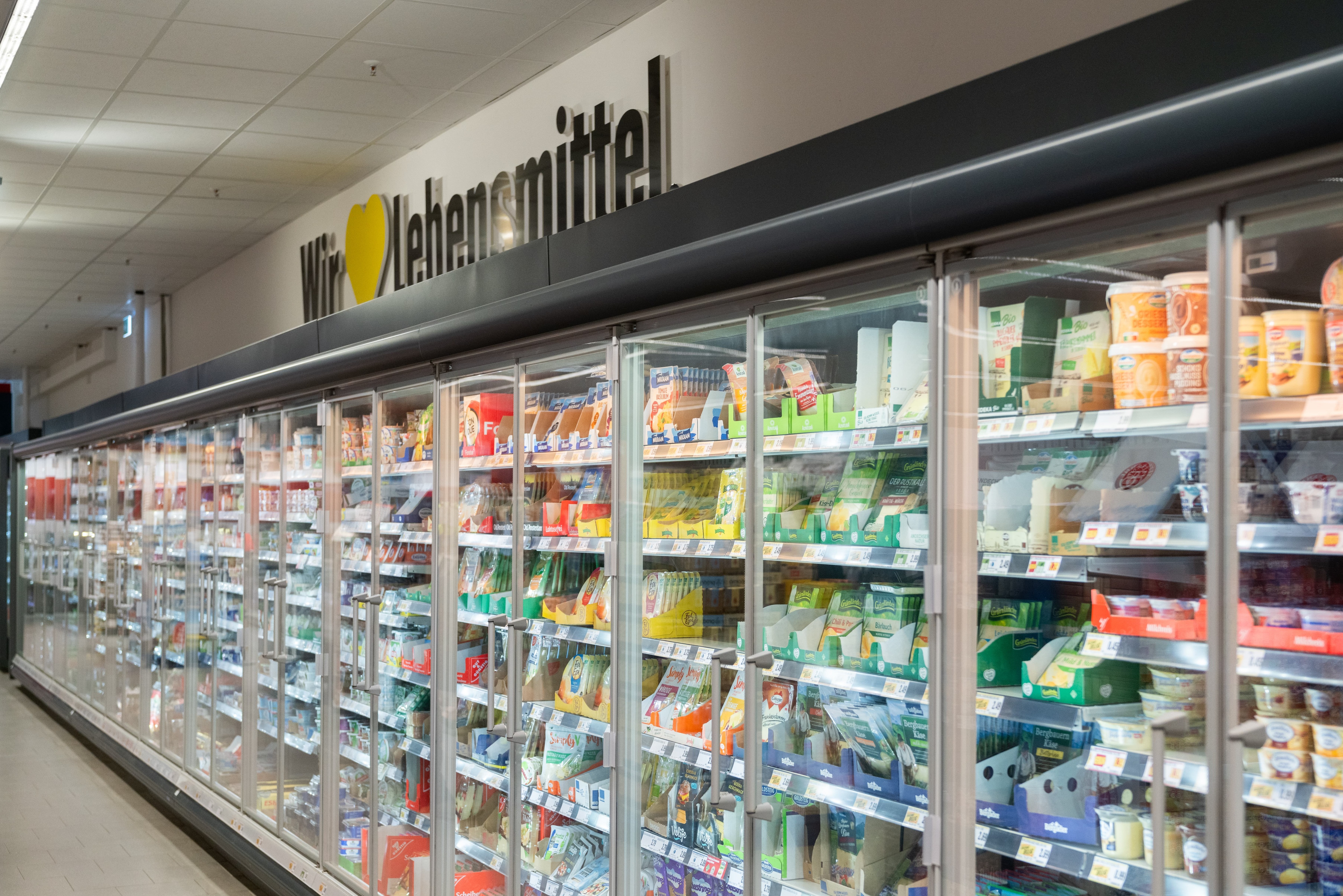 Ein langes Kühlregal mit Molkereiprodukten. Darüber steht Wir lieben Lebensmittel.