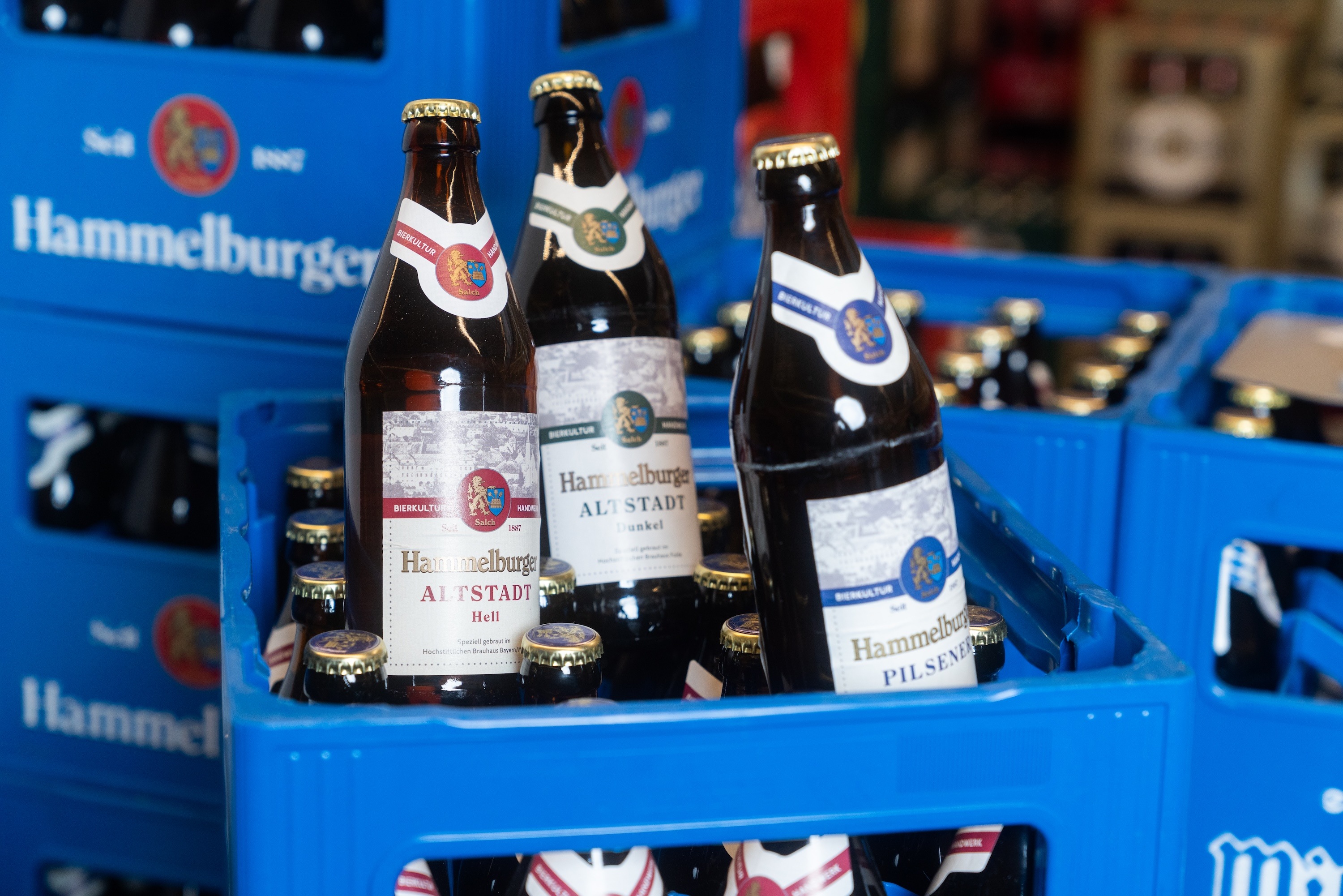 Drei Flaschen und mehrere Kisten der Biersorte Hammelburger Altstadt.