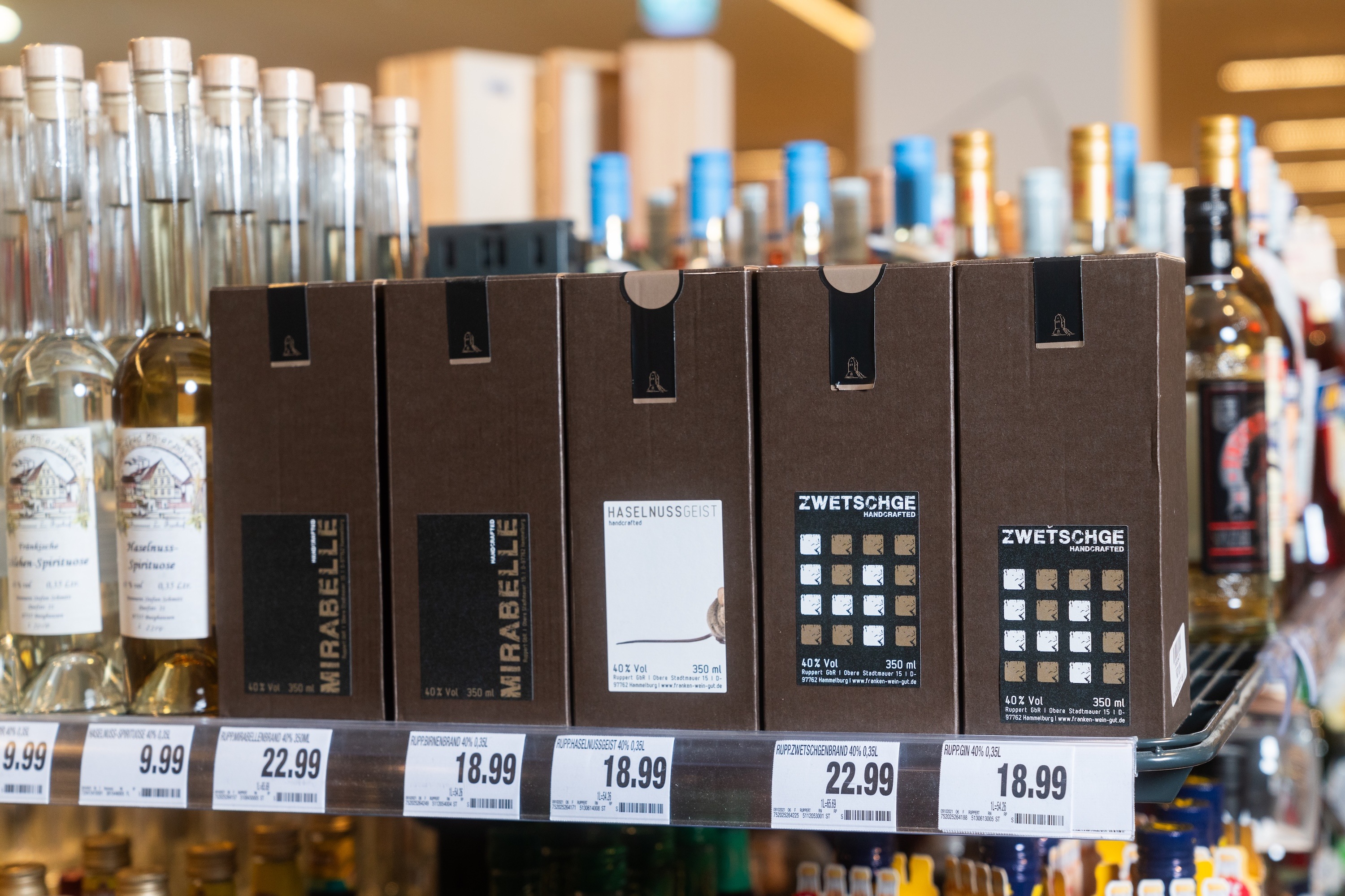 Ein Regal mit Spirituosen in dunkelbraunen Pappkartons.