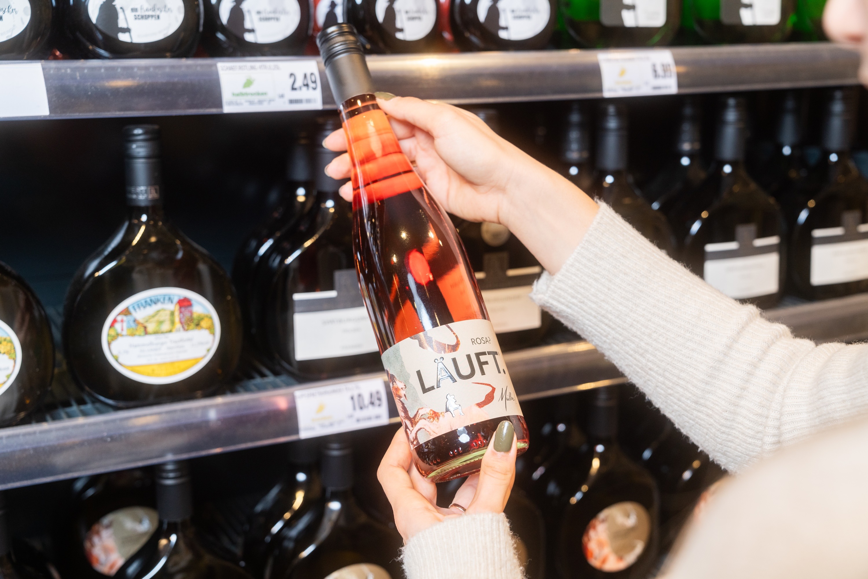 Zwei Hände halten eine Flasche Roséwein.