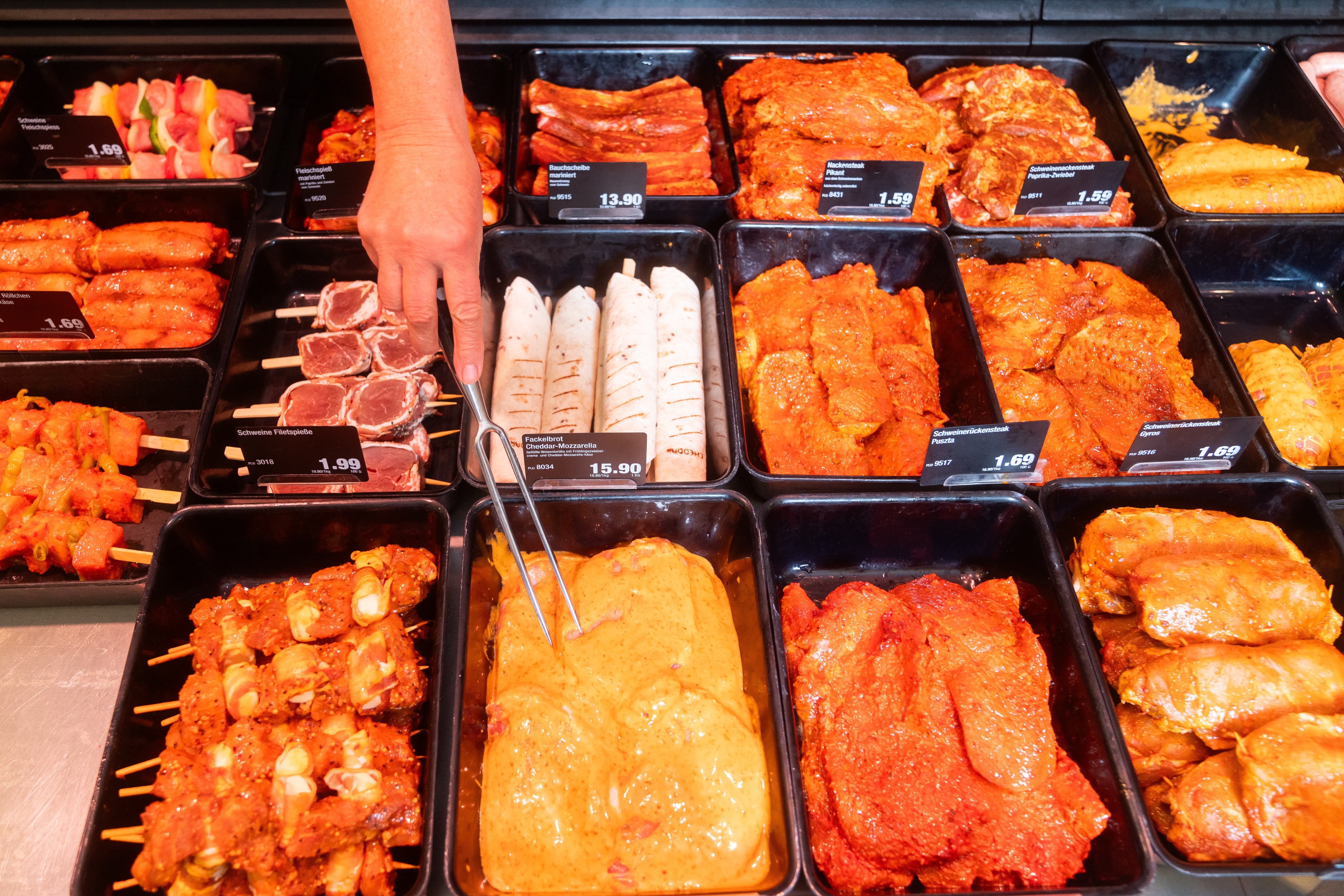 Verschiedene marinierte Fleischsorten mit Preisschildern in einer Auslage.