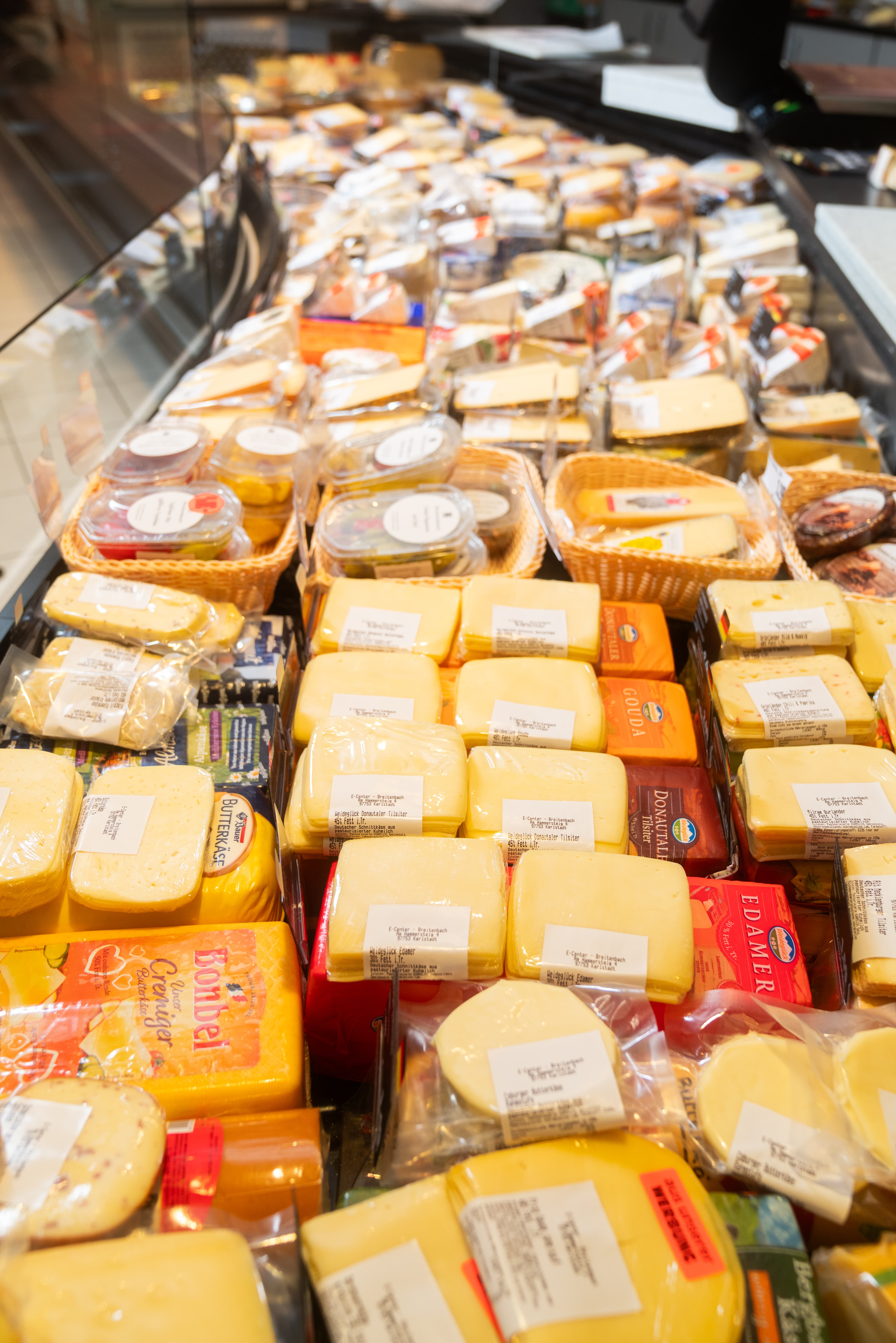 Verschiedene abgepackte Käsesorten in einer Auslage.