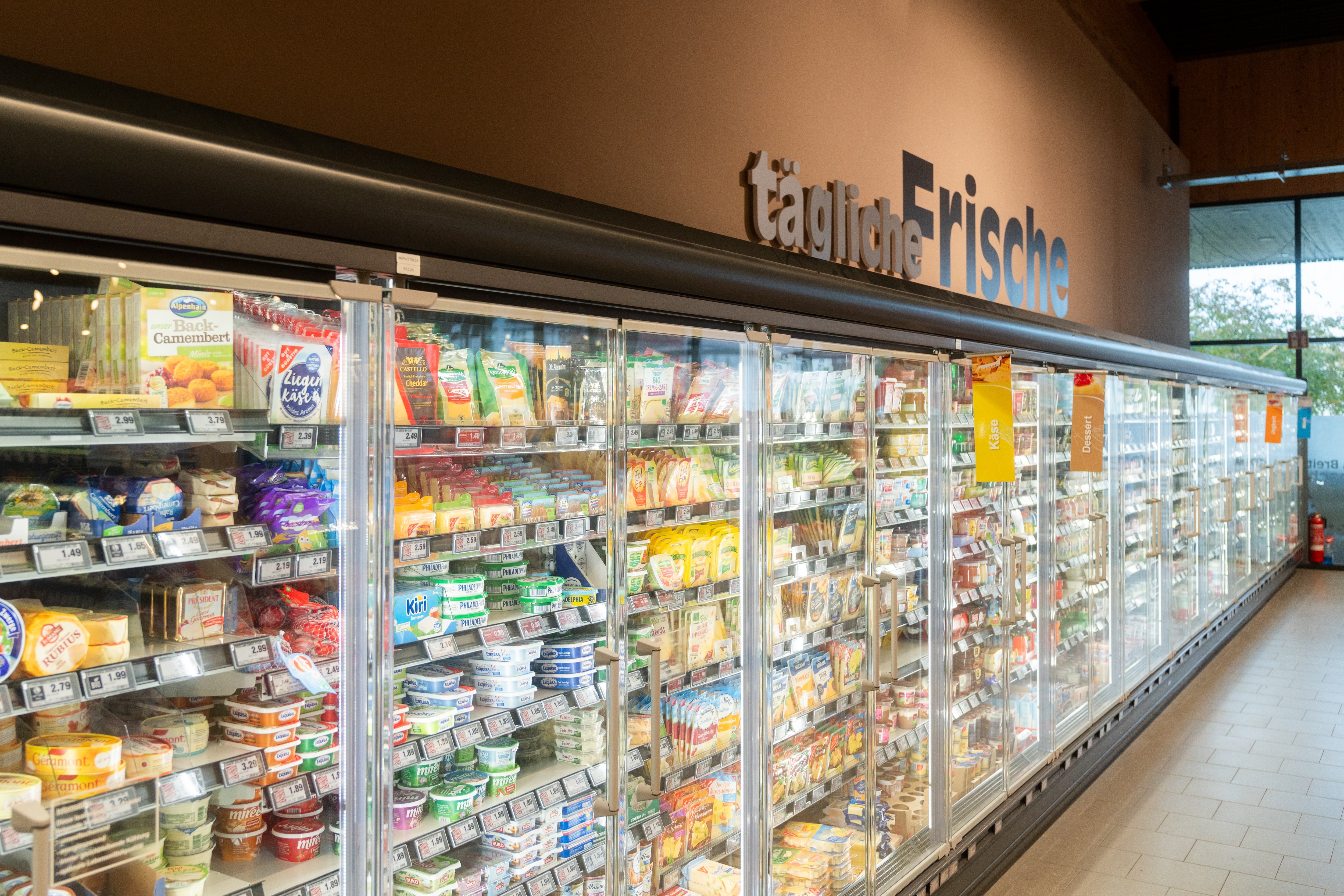Kühlschränke mit Molkereiprodukten. Darüber steht „tägliche Frische“.