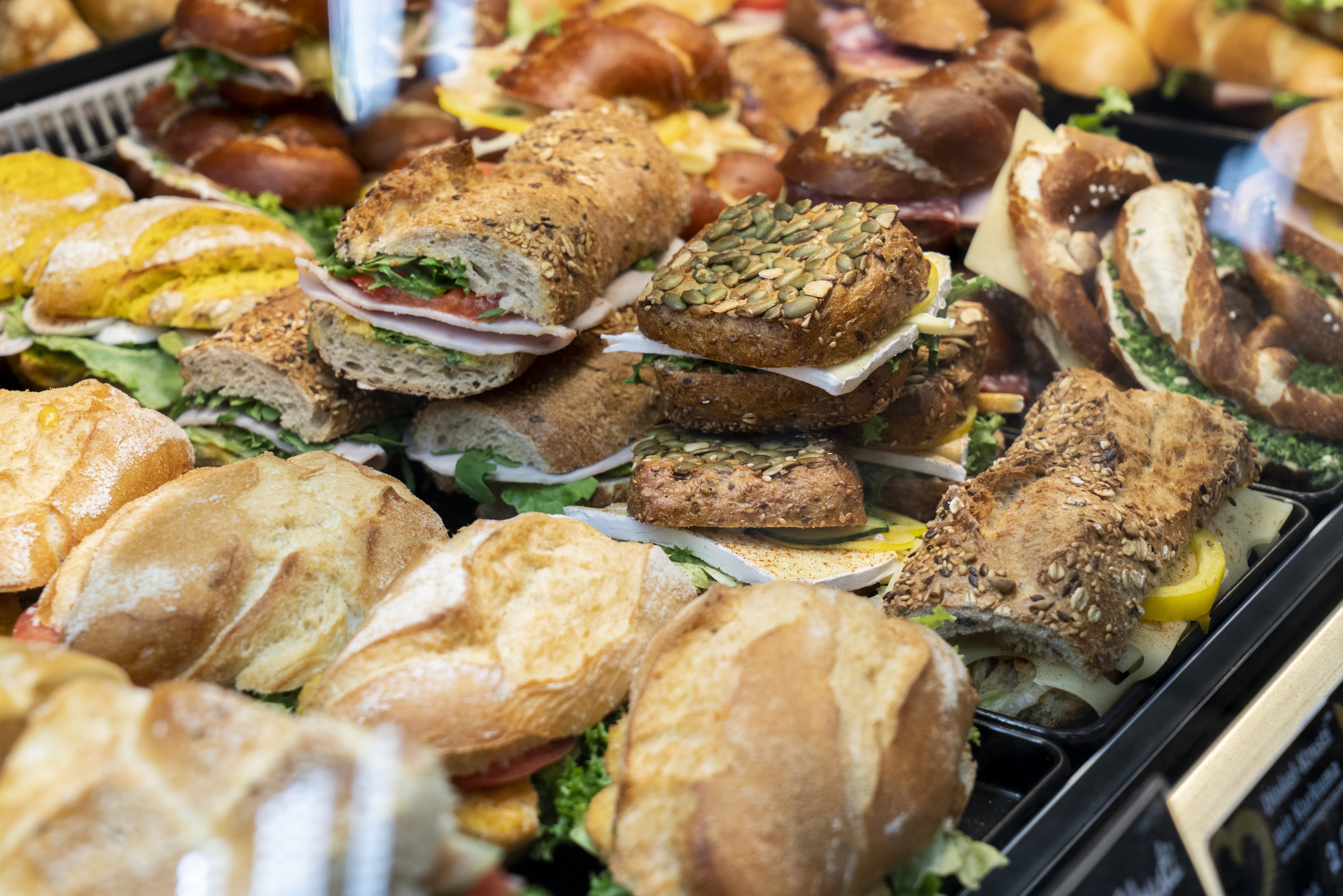 Close-Up verschiedener belegter Brötchen, Brezeln und Croissants in der Auslage eines Bäckers.