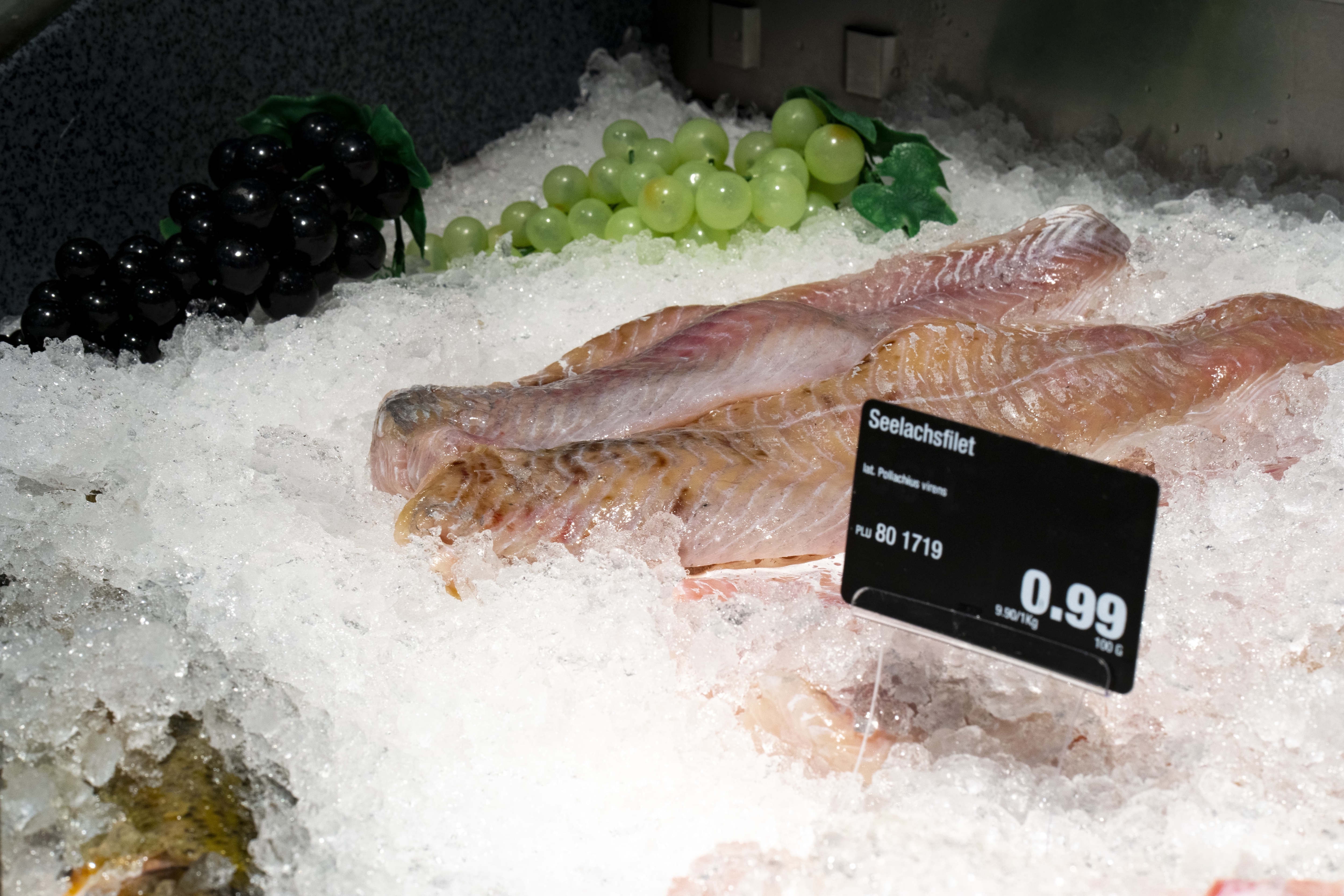 Fisch auf Eis mit künstlichen Weintrauben zur Dekoration.