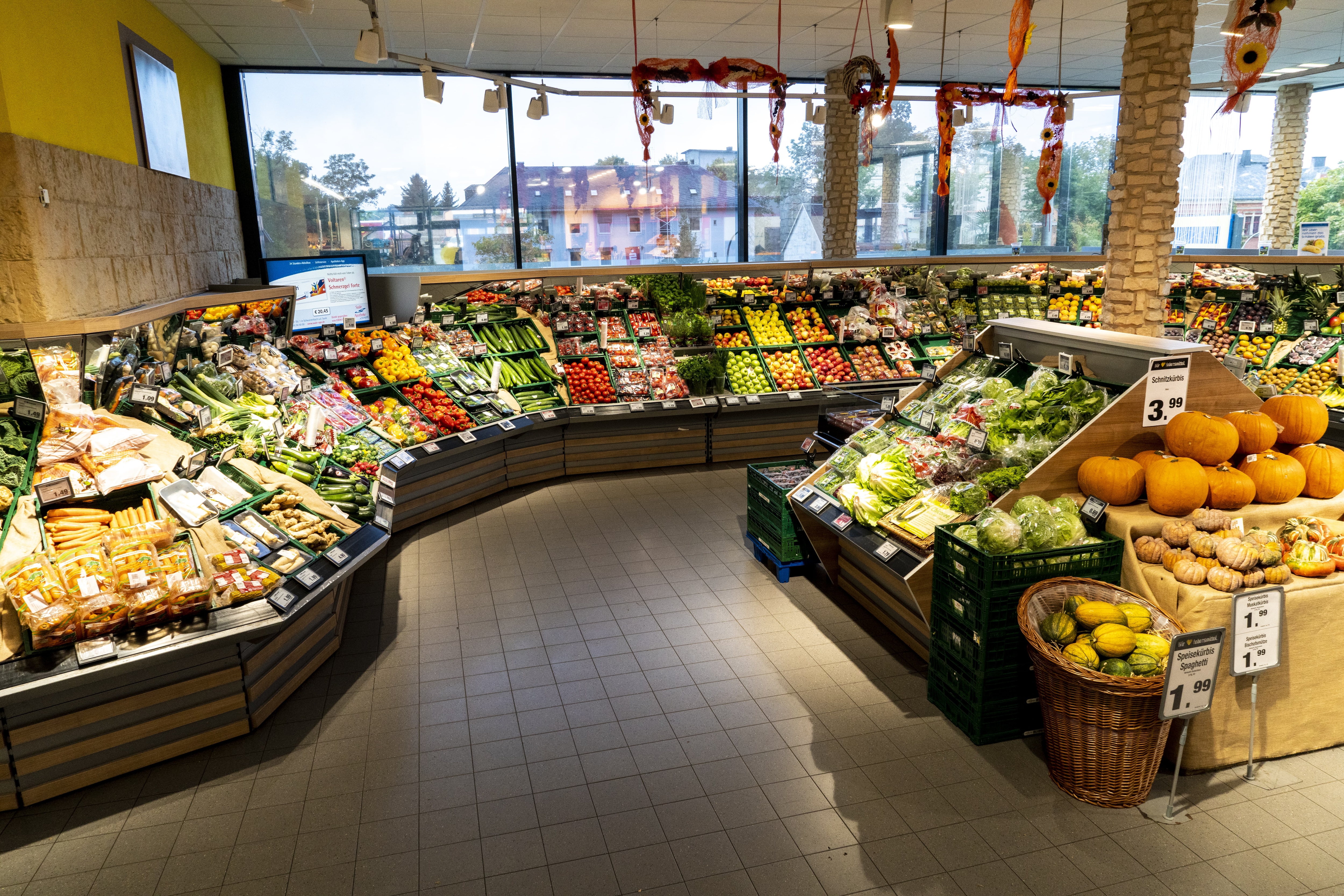 Die Obst- und Gemüseabteilung eines EDEKA-Markts mit von der Decke hängender saisonaler Dekoration.