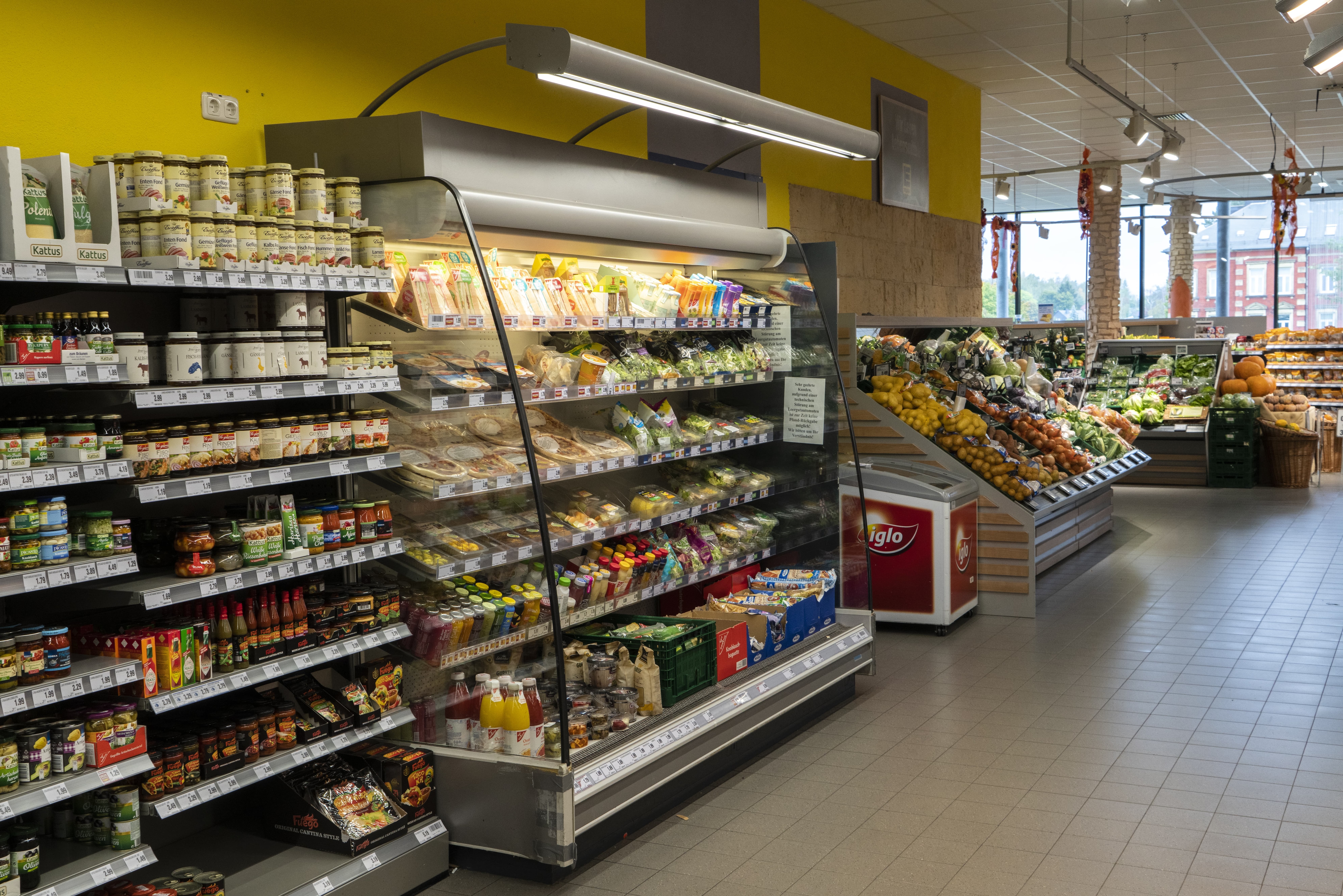 Ein Regal mit Smoothies und abgepackten Sandwiches, das sich an die Obst- und Gemüseabteilung des EDEKA-Markts anschließt.