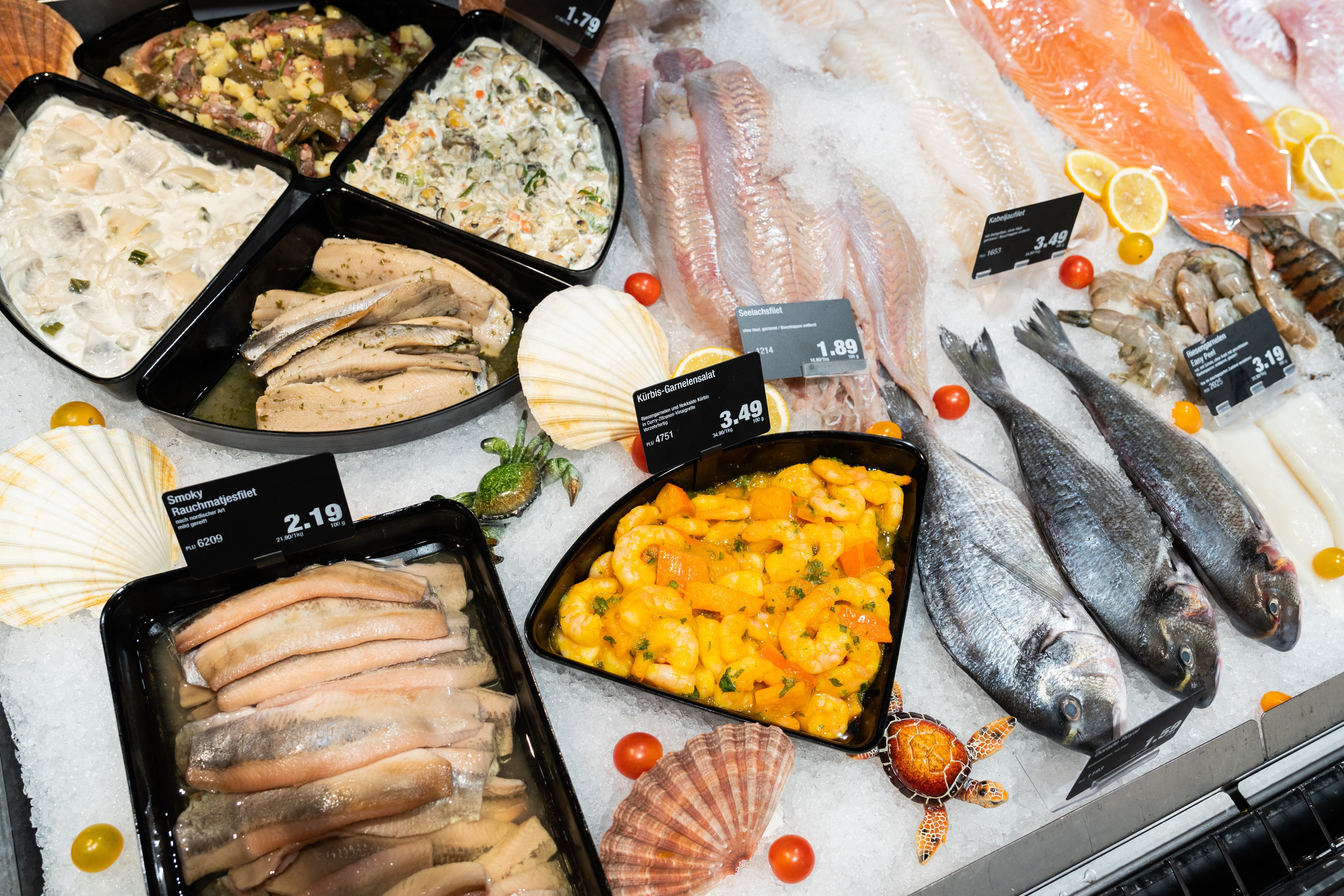 Verschiedene Fischwaren mit Preisschildern in einer Auslage der Fischtheke.