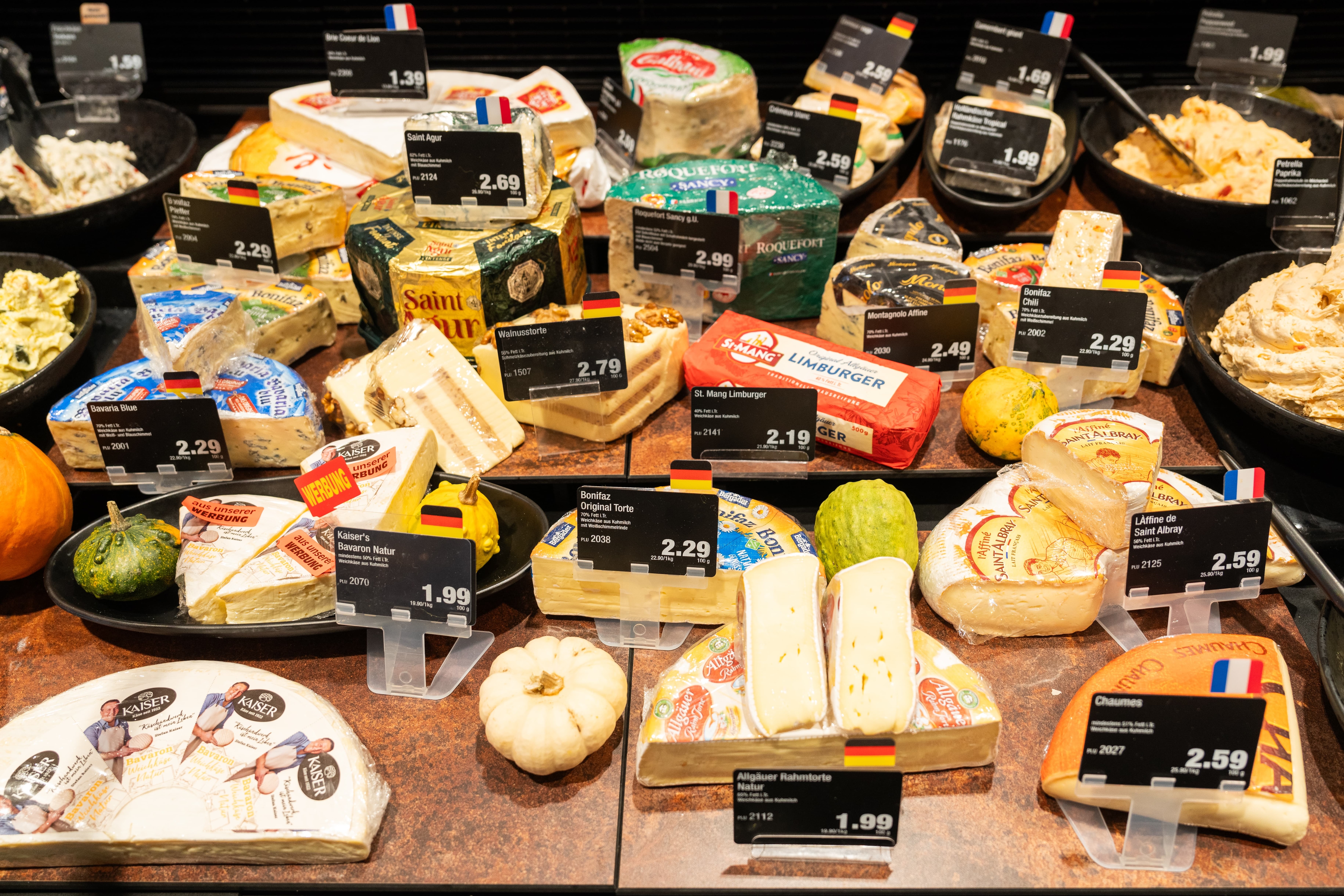 Verschiedene Käsewaren mit Preisschildern in einer Auslage der Käsetheke.