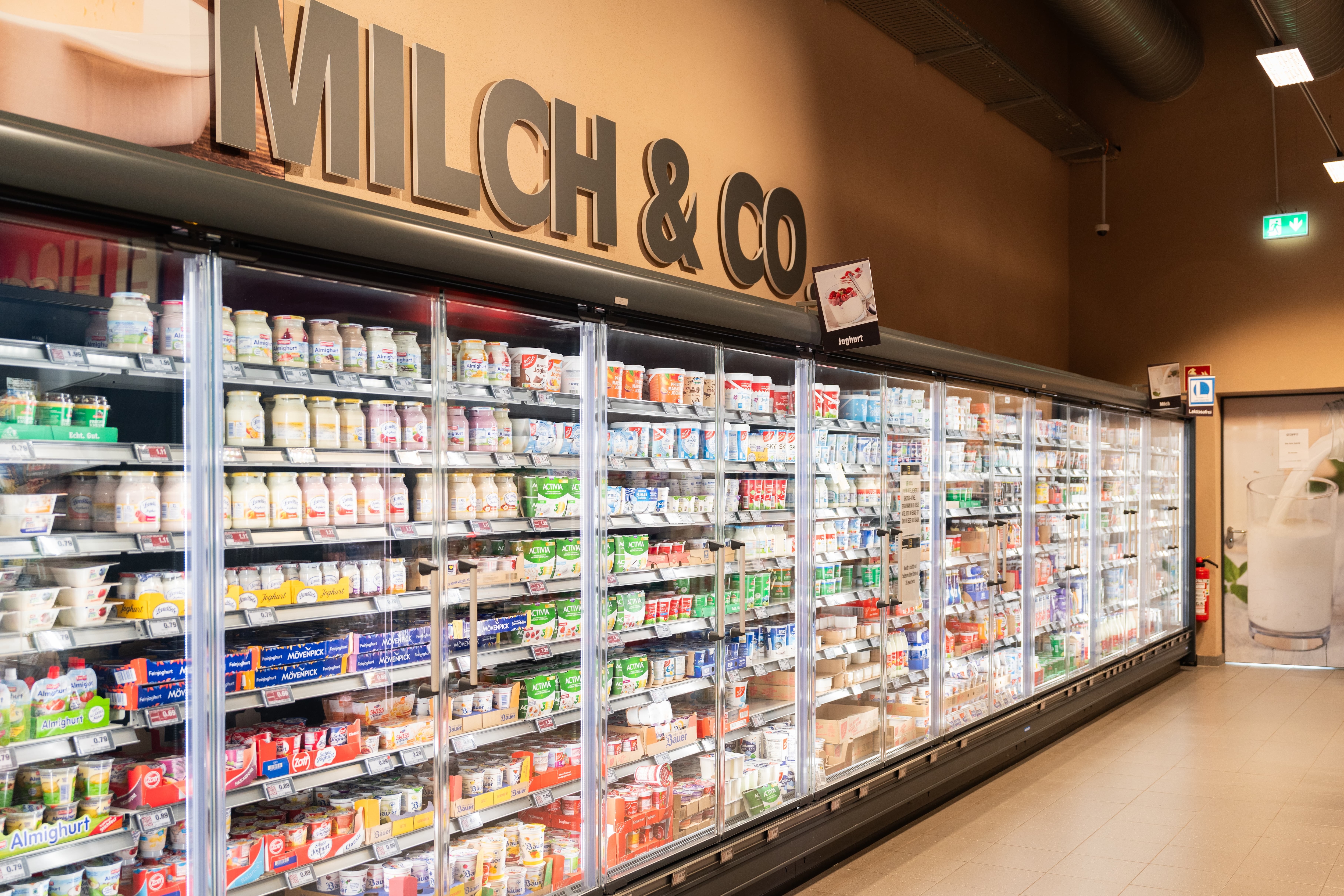 Eine Kühlabteilung eines Edeka-Marketes mit verschieden Waren in den Schränken. Über den Kühlschränken steht ein Schriftzug mit "Milch & Co.".