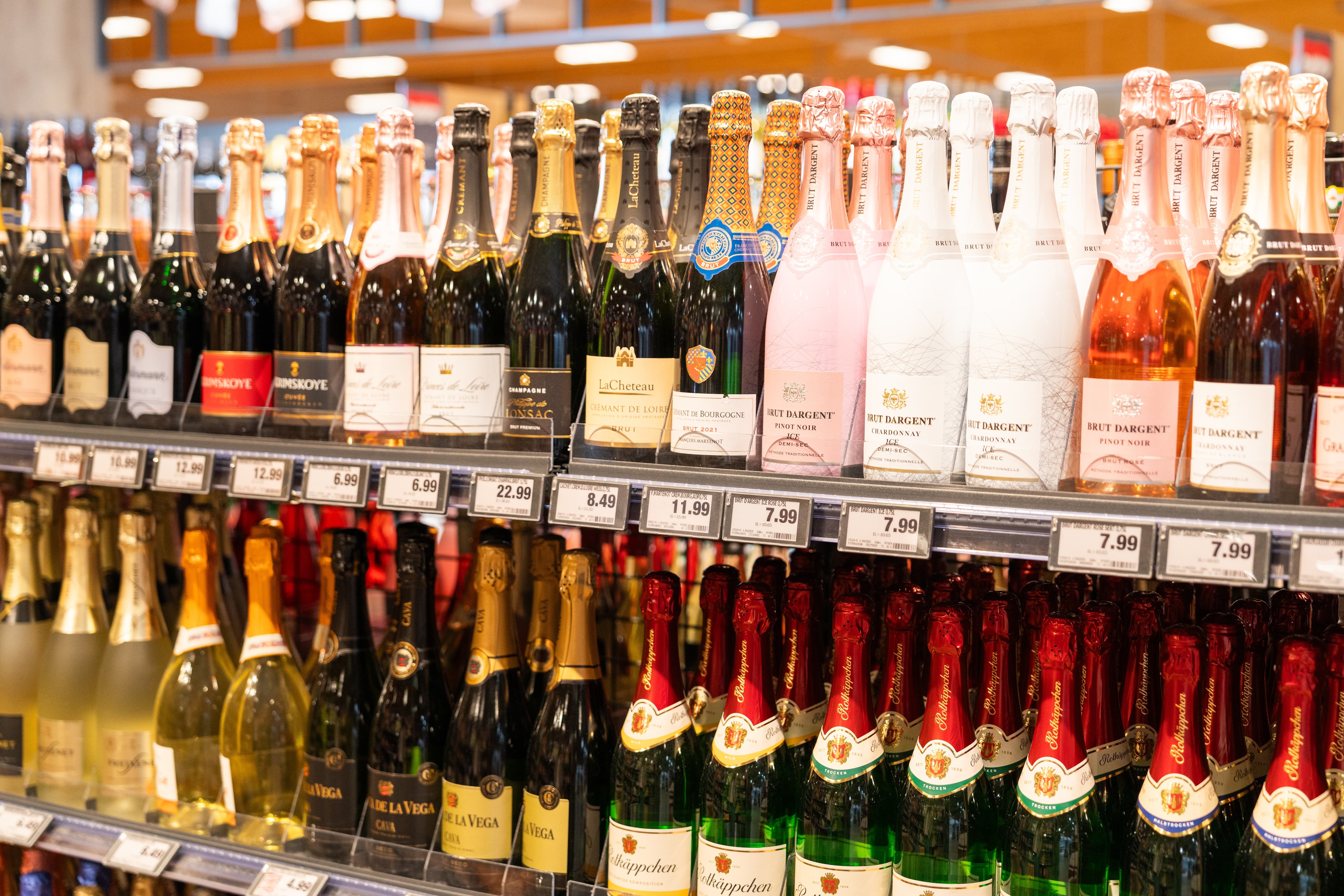 Unterschiedliche Sekt-Sorten aufgereiht in einem Regal.