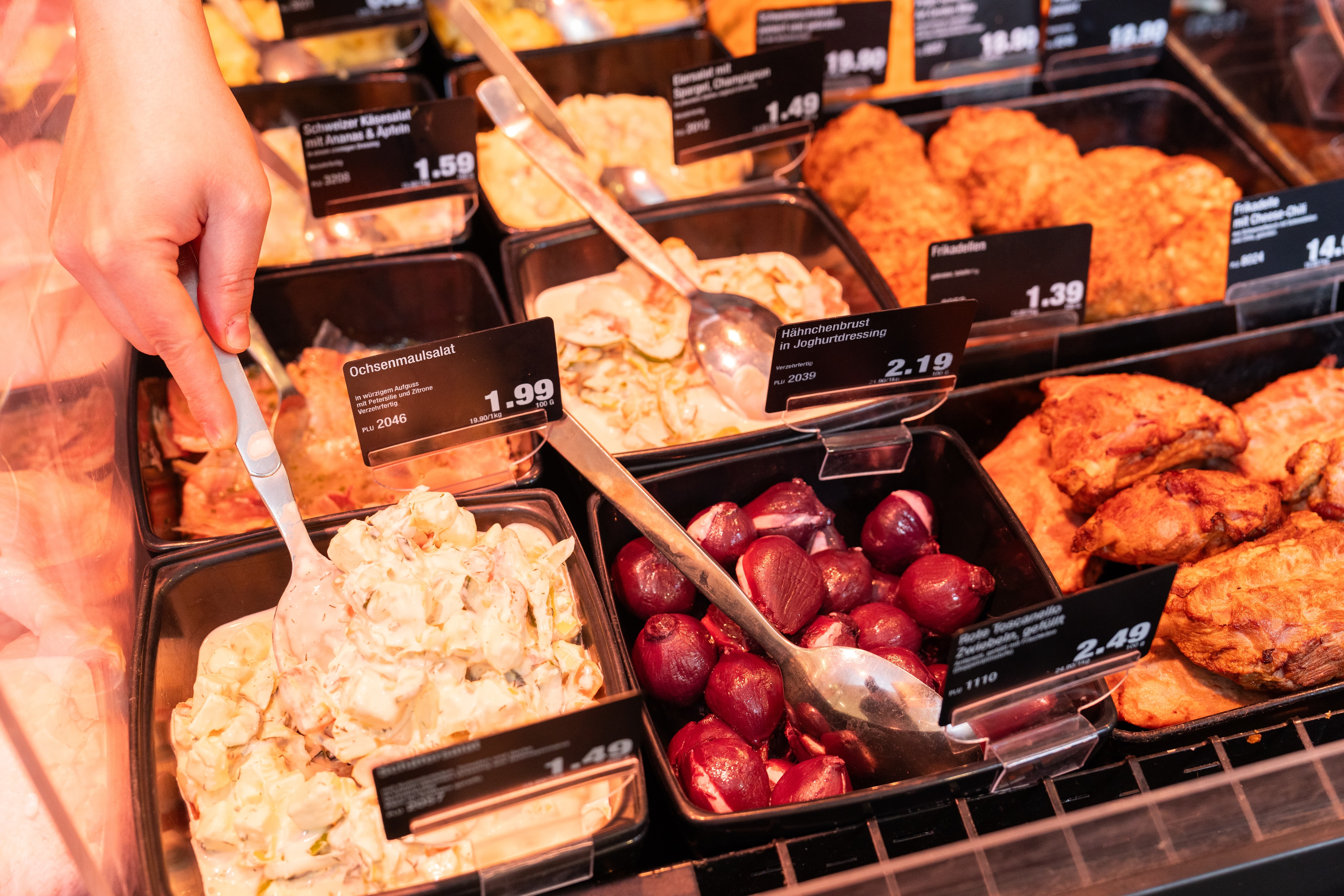 Verschiedene Fleischsalate und andere Fleischspezialitäten in der Auslage einer Bedientheke.