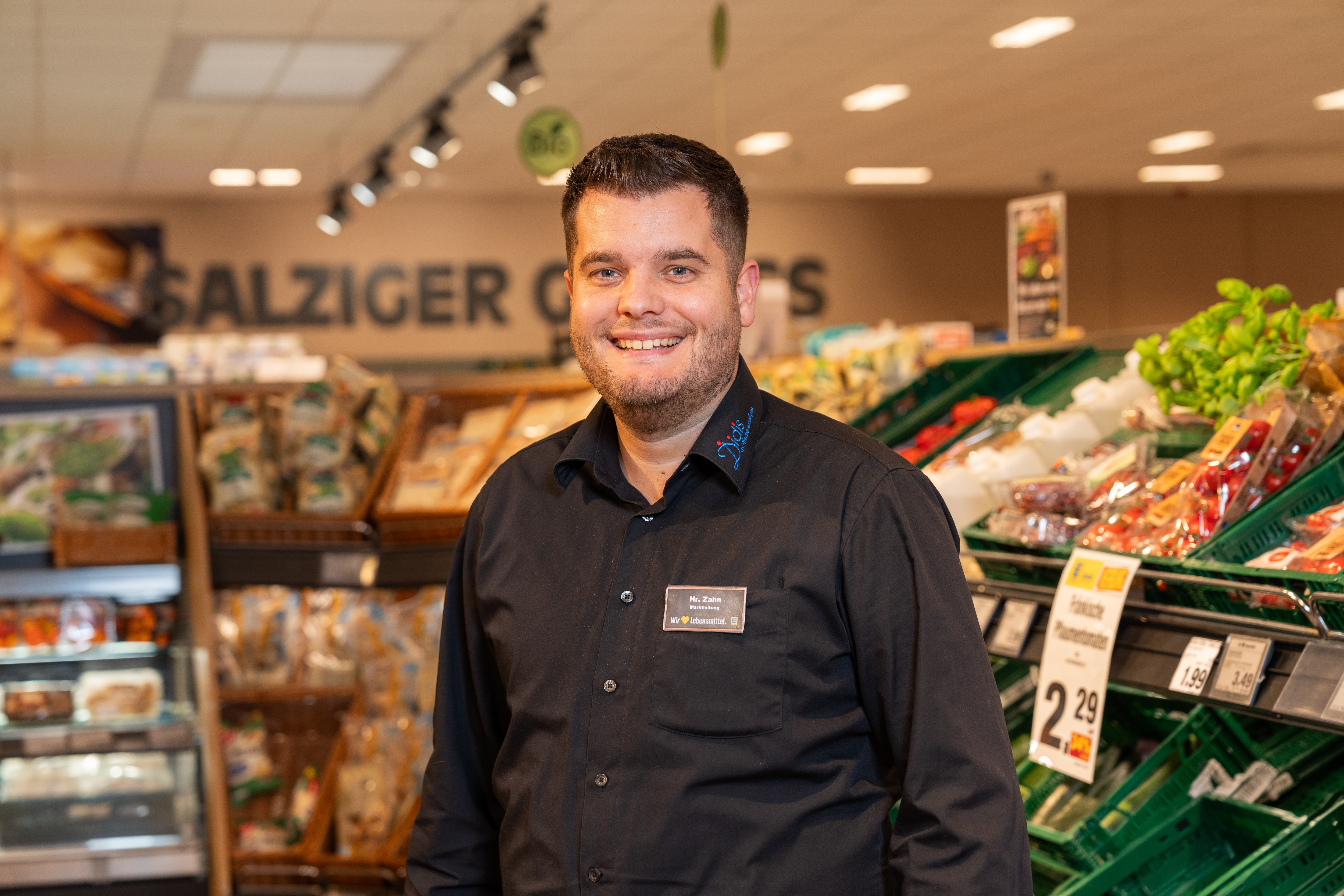 Der lächelnde Marktleiter eines EDEKA-Marktes.