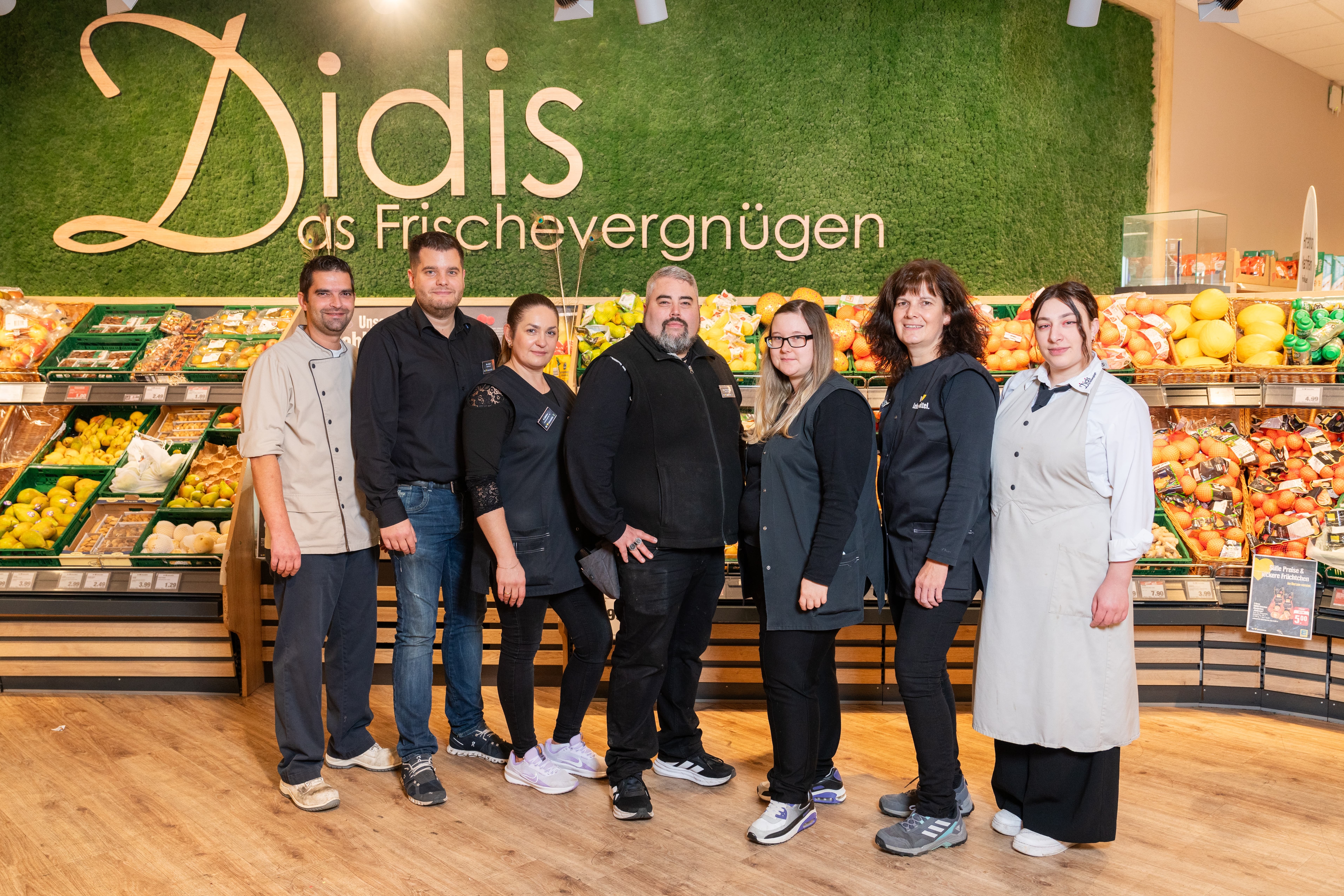 Ein Gruppenfoto der Mitarbeitenden eines EDEKA-Marktes in der Obst- und Gemüseabteilung.