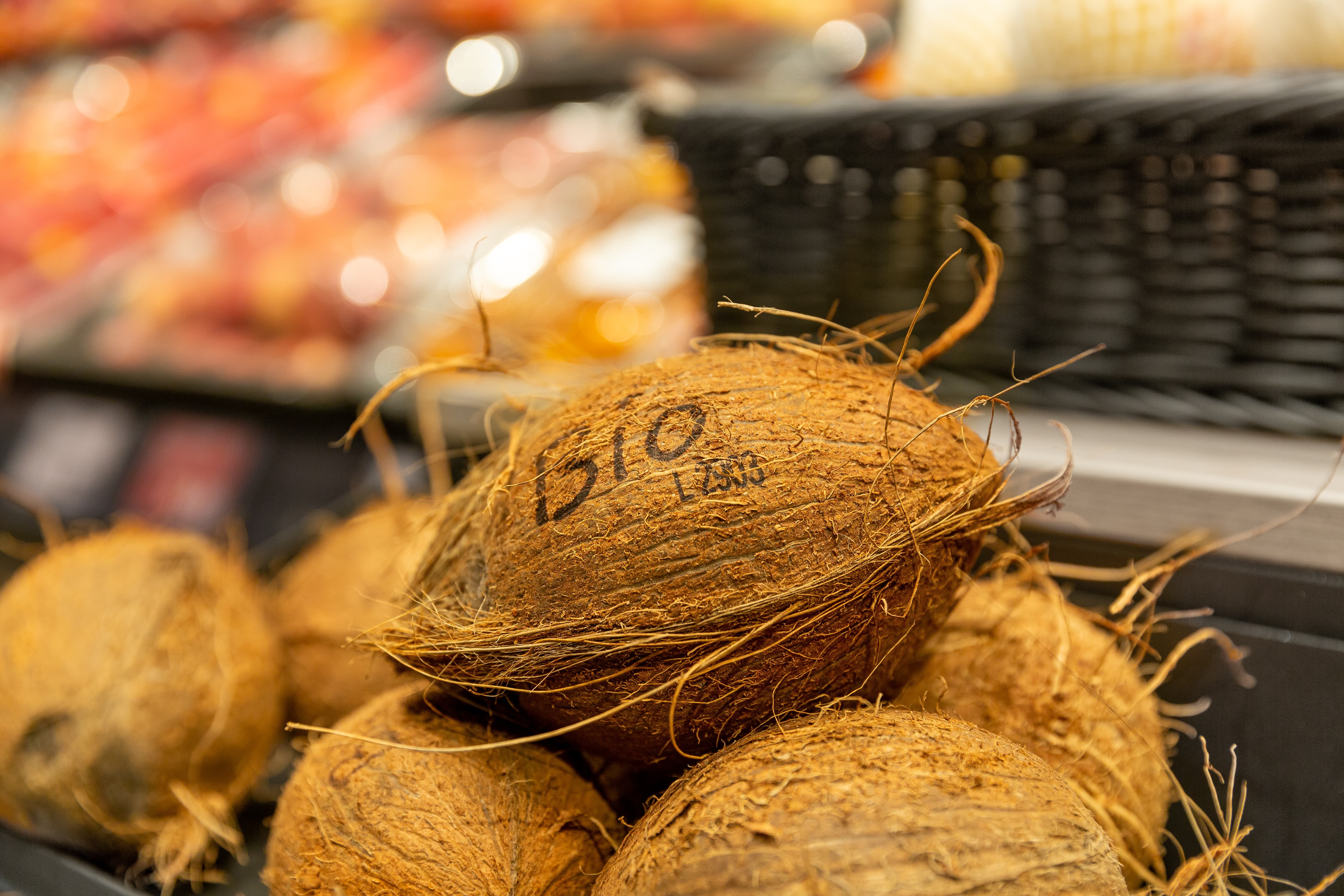Nahaufnahme einer Bio-Kokosnuss in einem Korb voller Kokosnüsse.