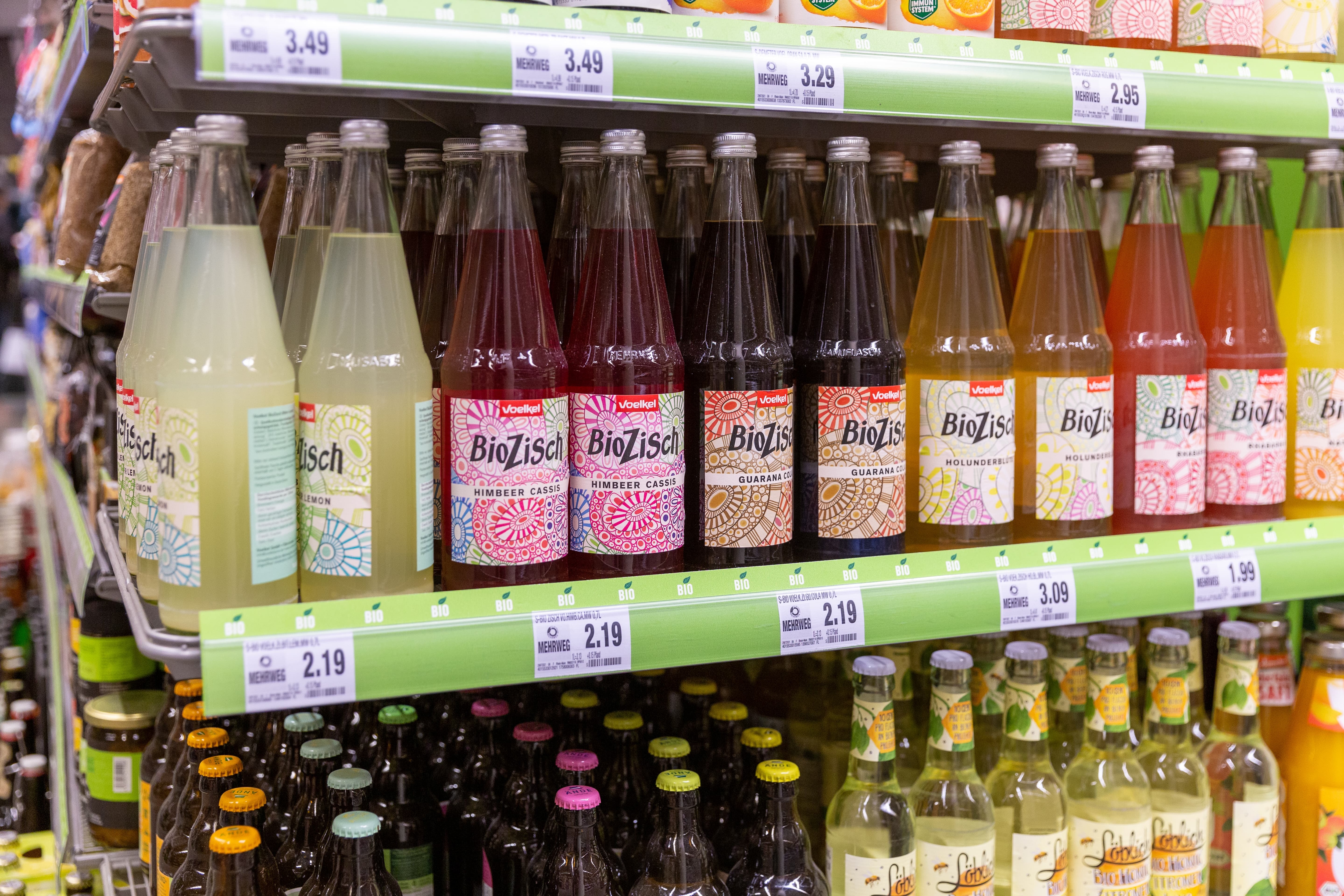Nahaufnahme eines Regals mit voelkel BioZisch Flaschen.