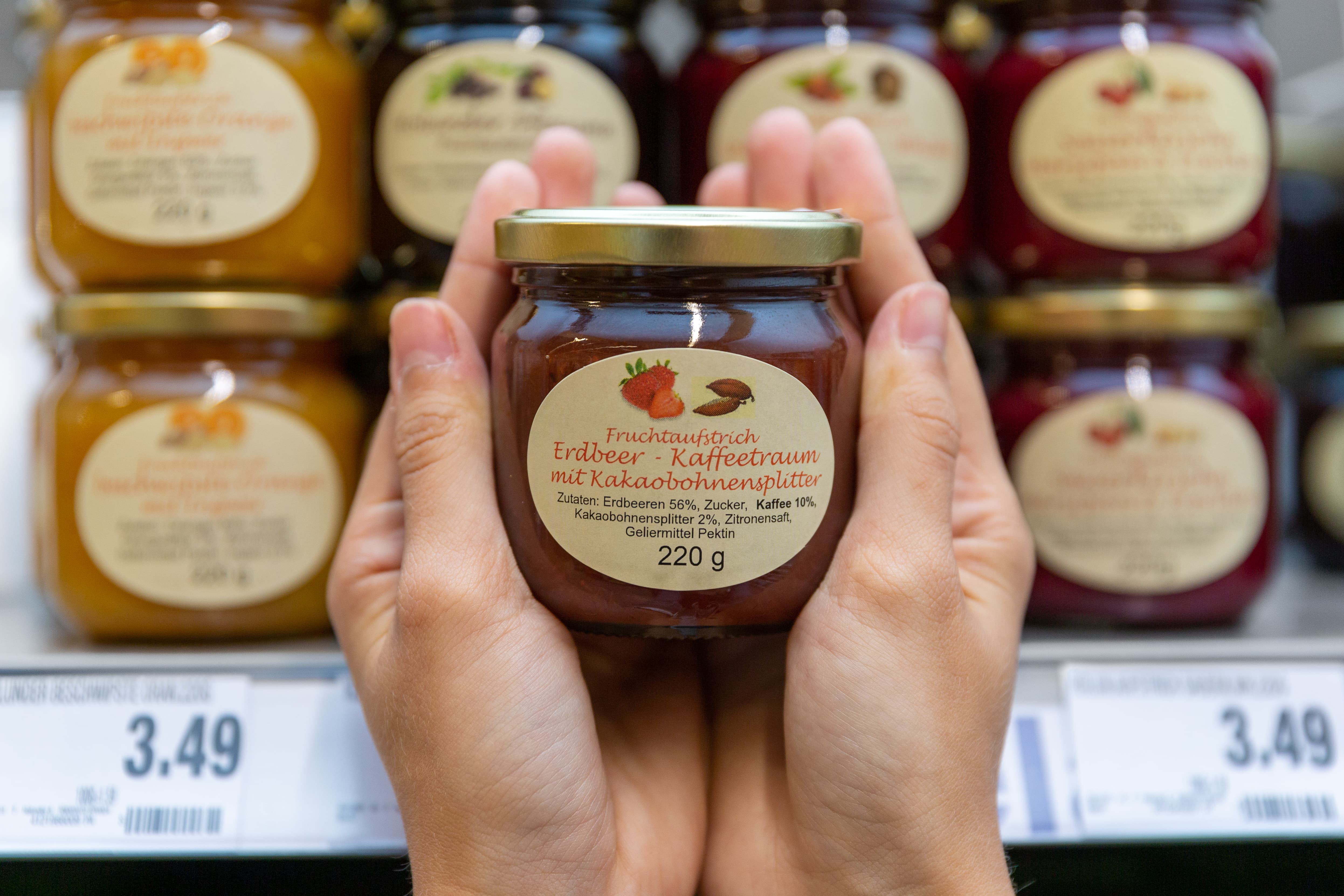 Zwei Hände halten ein Glass des regionalen Fruchtaufstrichs.