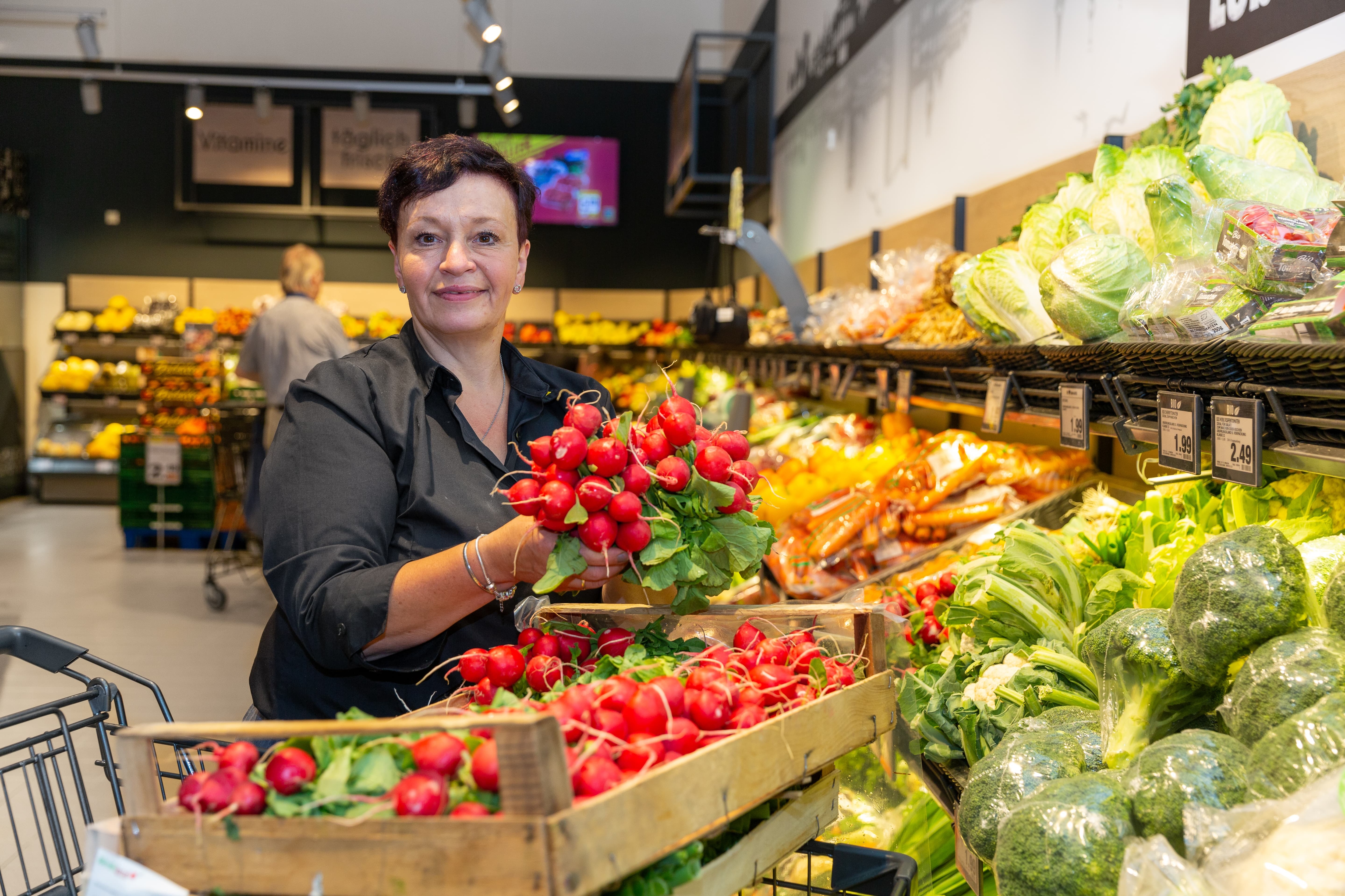 Eine Mitarbeiterin räumt Radieschen in die Auslage.