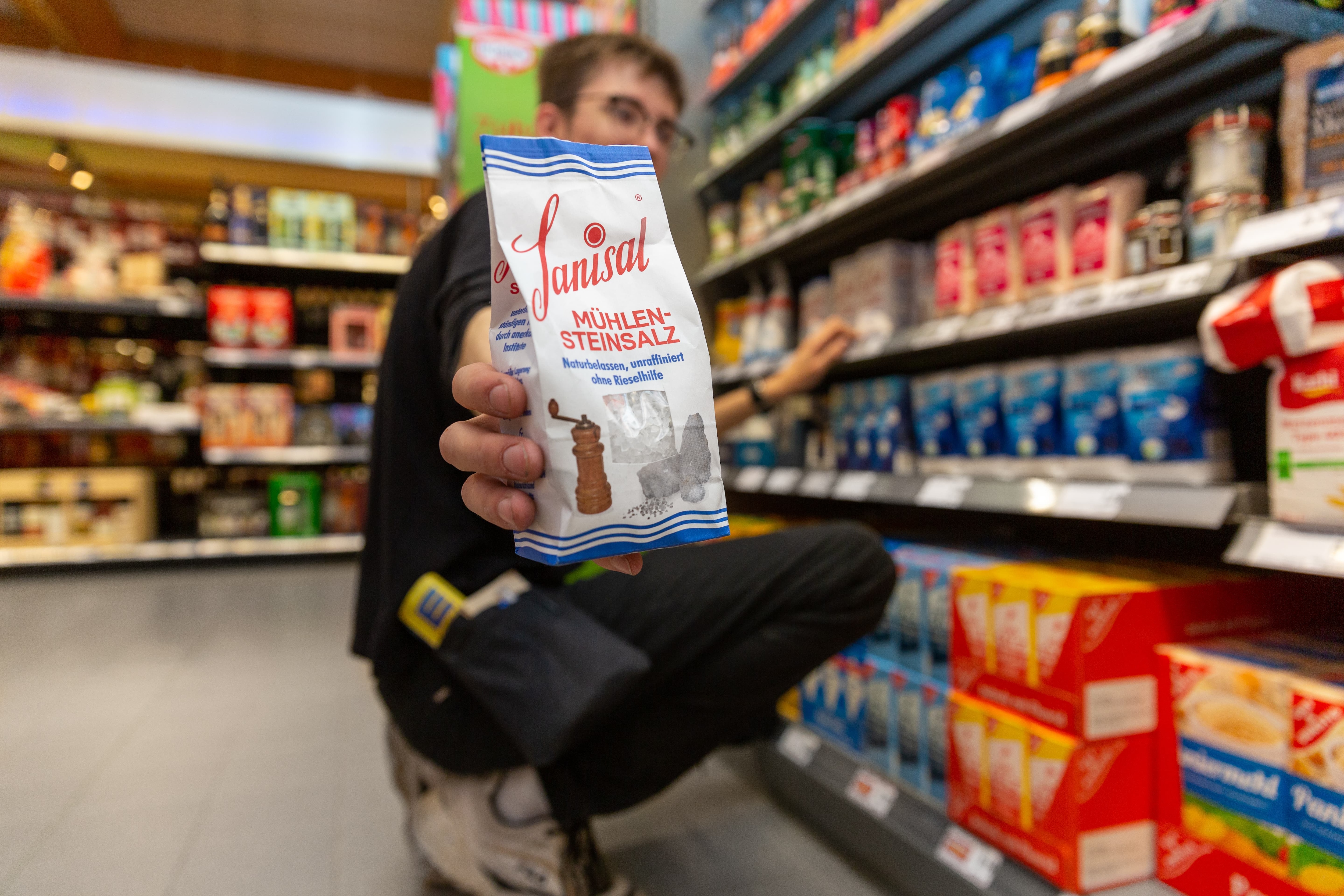 Ein Mitarbeiter hält eine Packung Salz in die Kamera.