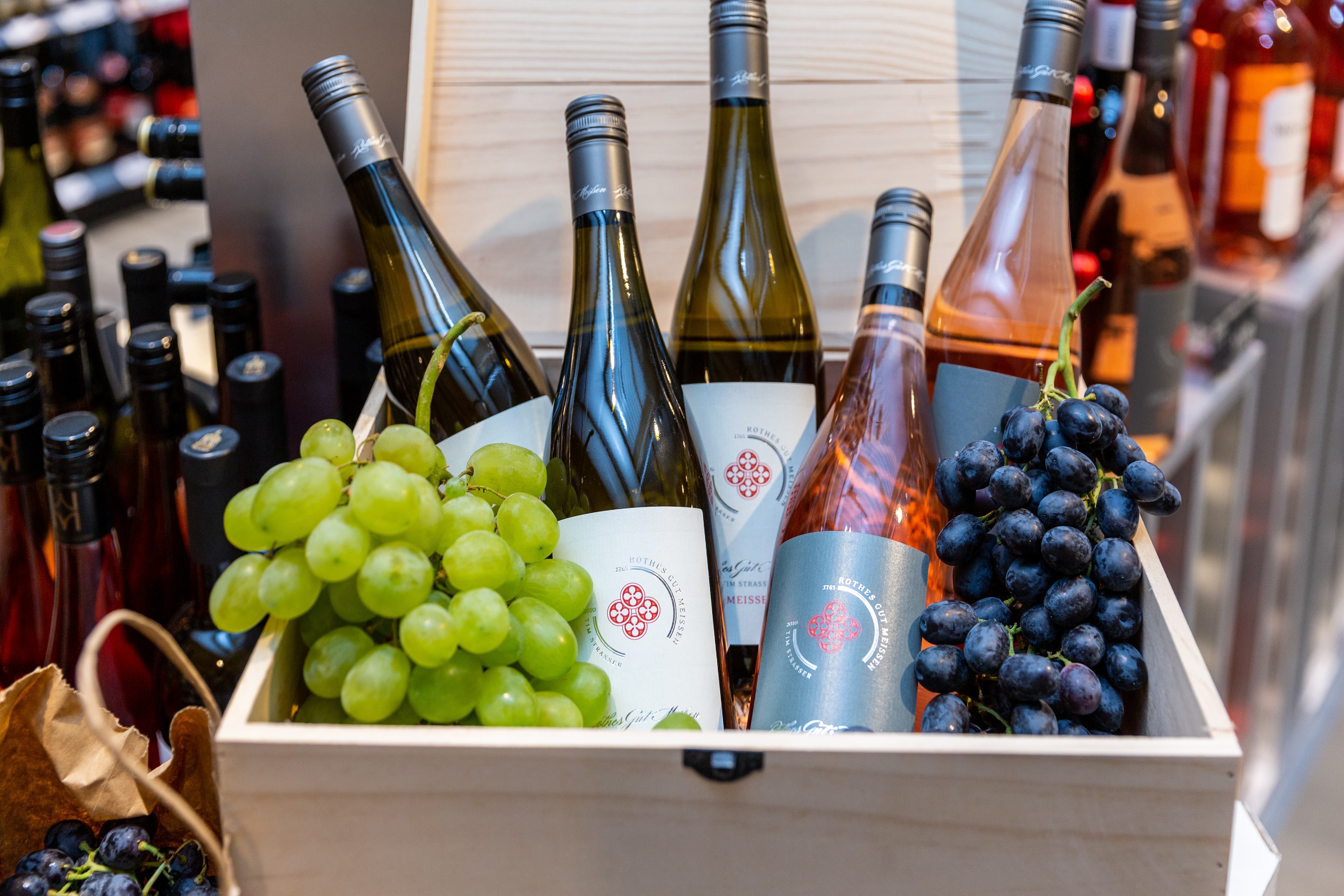 Eine offene Holzkiste mit Wein und Trauben.