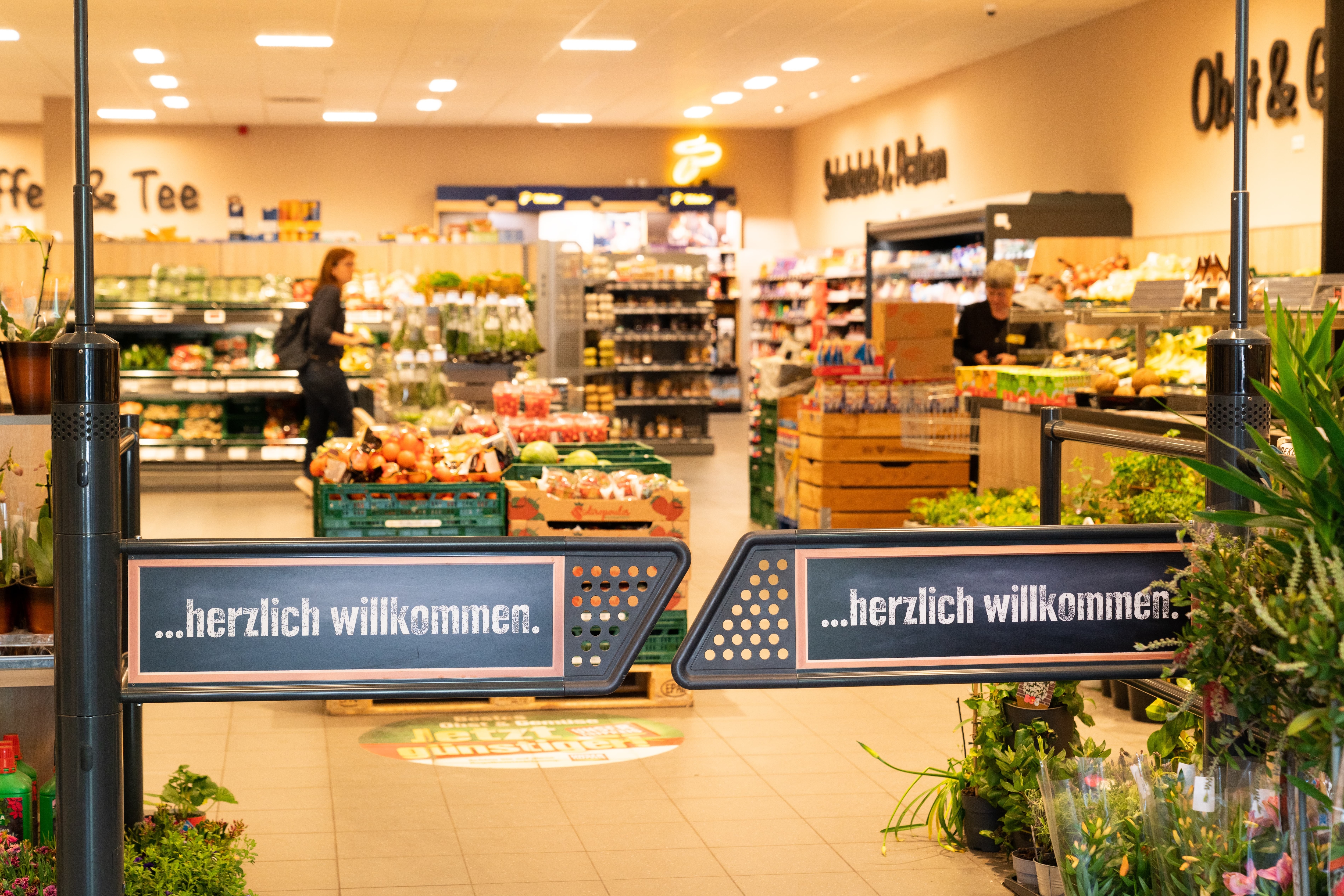 Eingangsschwingtor eines EDEKA-Marktes. Auf den Flügeln steht herzlich willkommen.