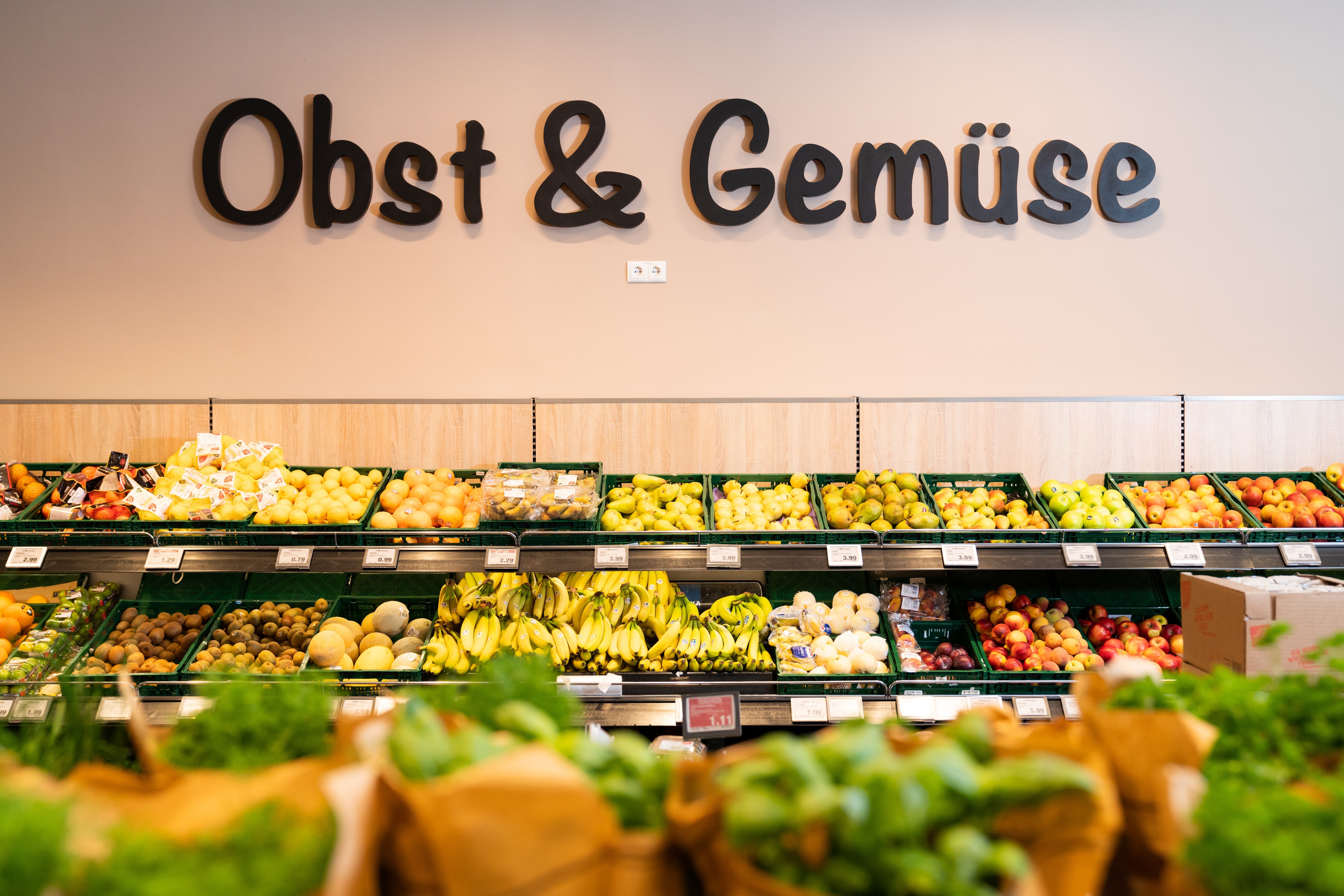 Obstregale in einem Supermarkt. An der Wand steht Obst und Gemüse.