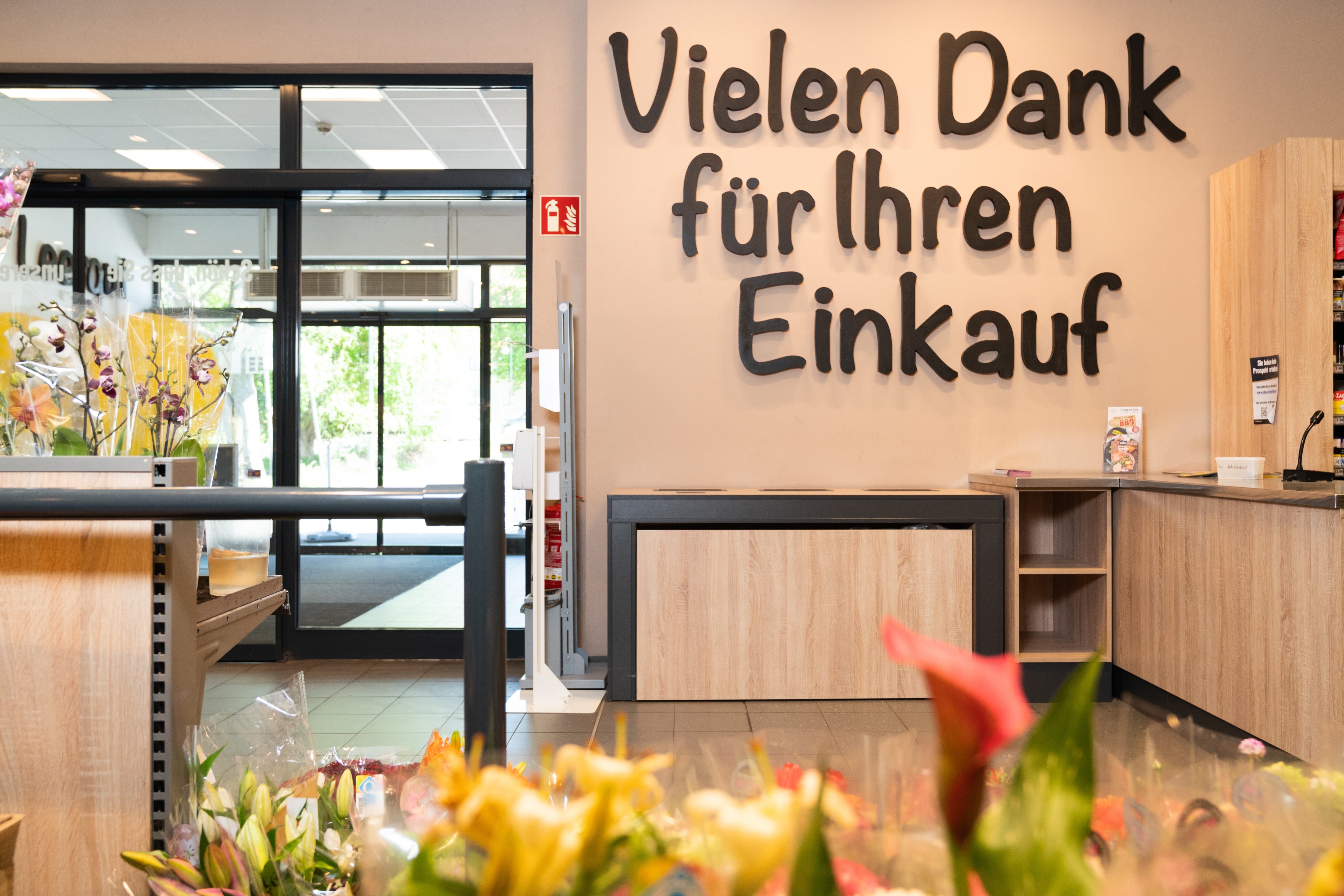 Am Ausgang eines Supermarktes ist ein Wandtattoo in schwarzer Schrift: Vielen Dank für Ihren Einkauf.