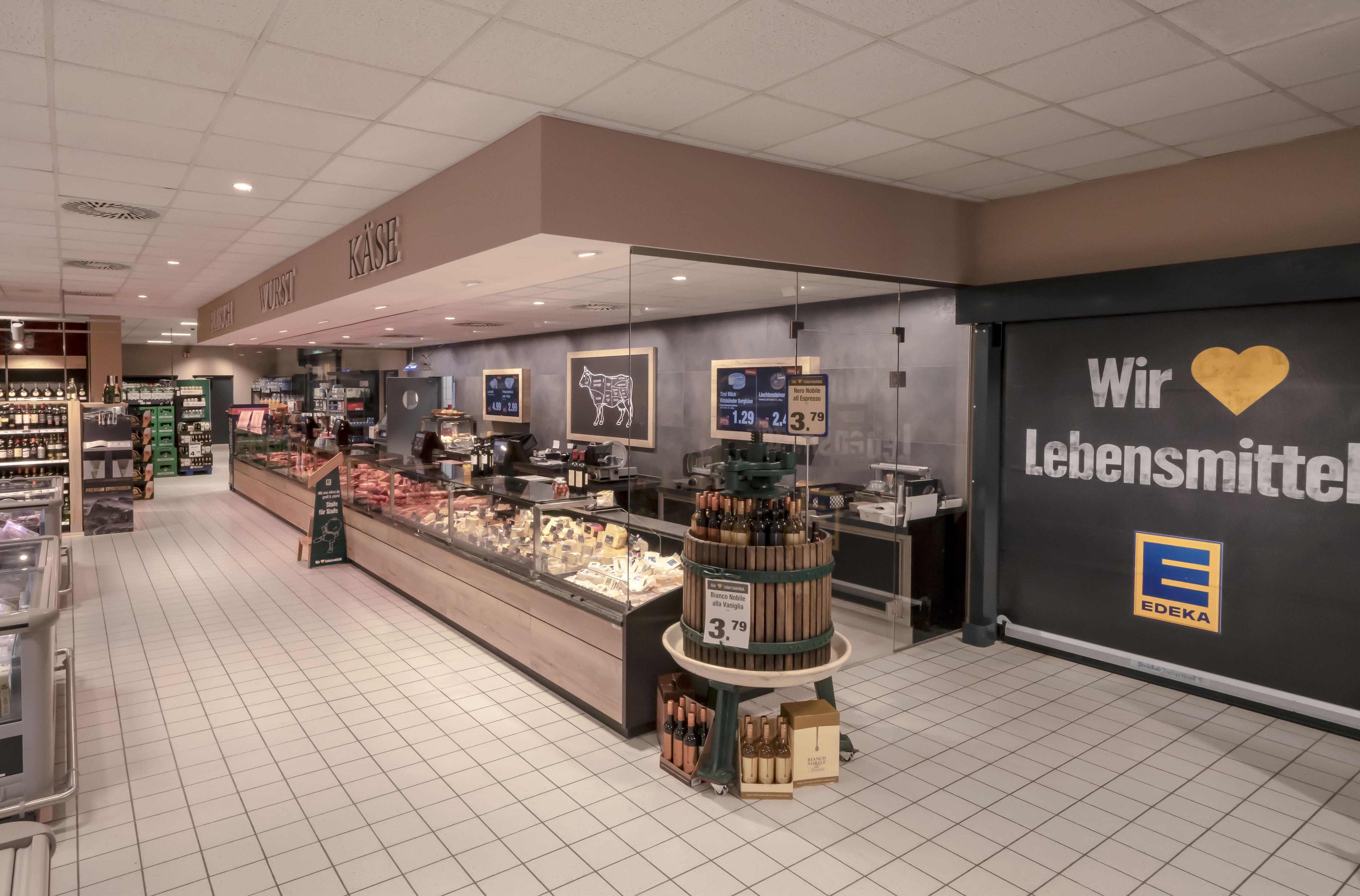 Die Bedientheke eines EDEKA-Markts, mit Front in Holzoptik und grauen Kacheln am Boden.