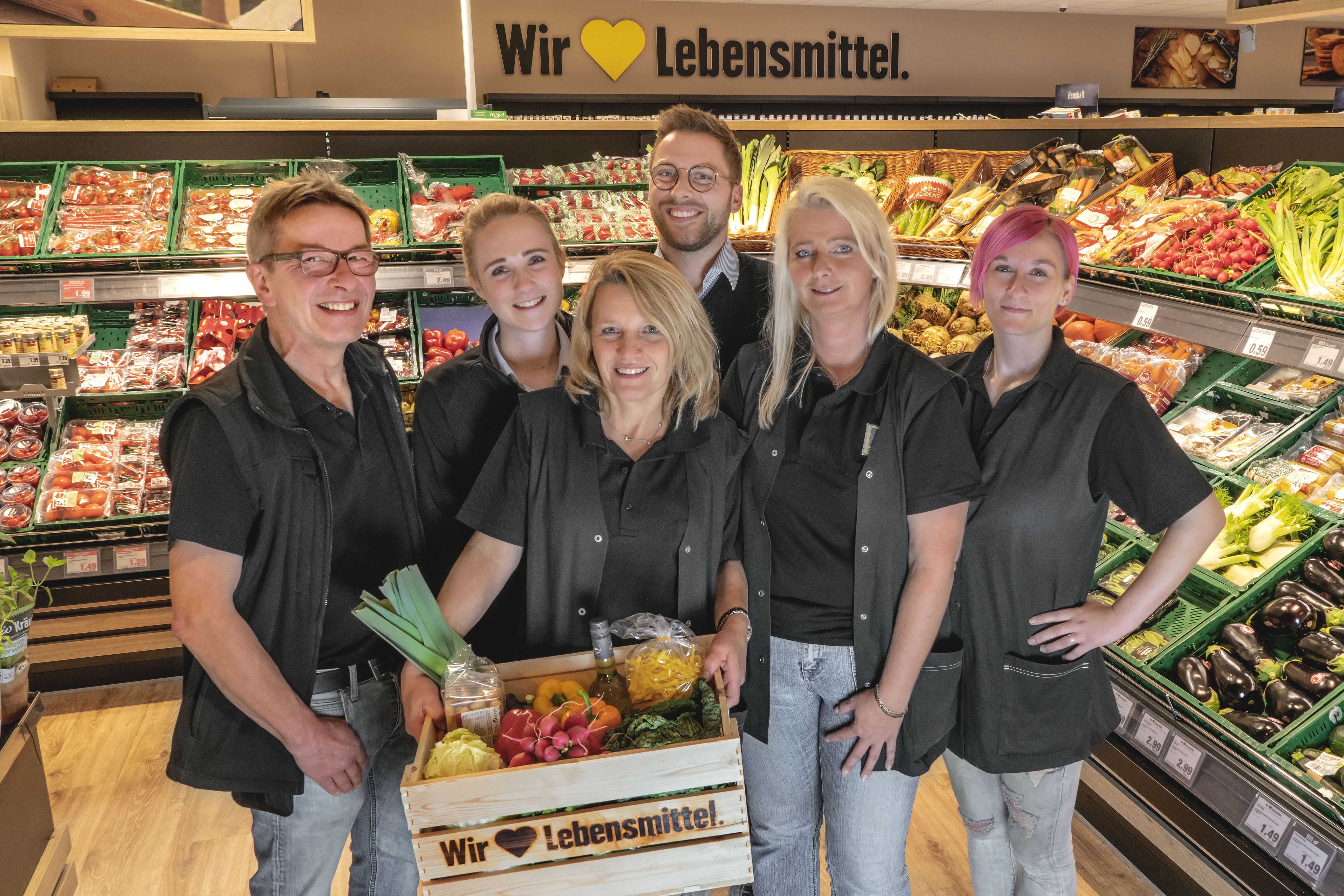 Gruppenfoto des Teams dieses EDEKA-Markts, aufgenommen in der Obst- und Gemüseabteilung.