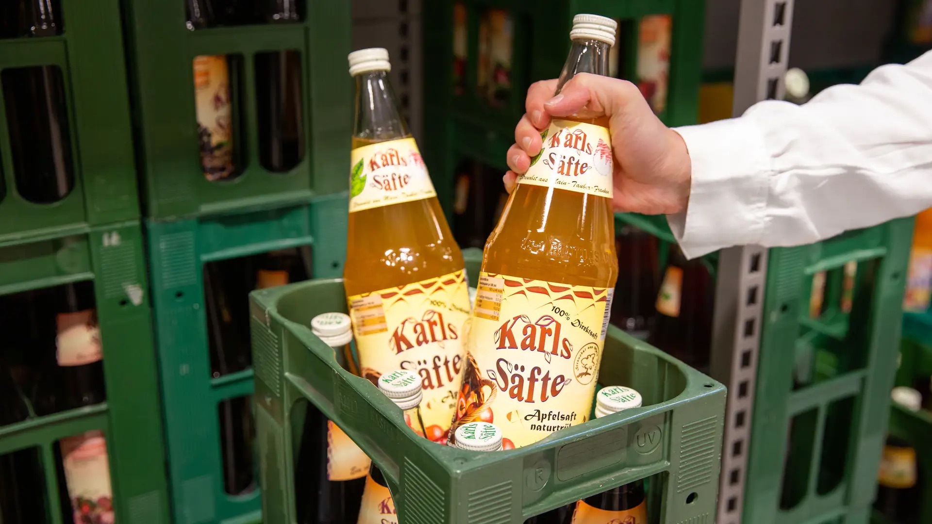 Eine Hand nimmt eine Flasche Apfelsaft aus einer Kiste.