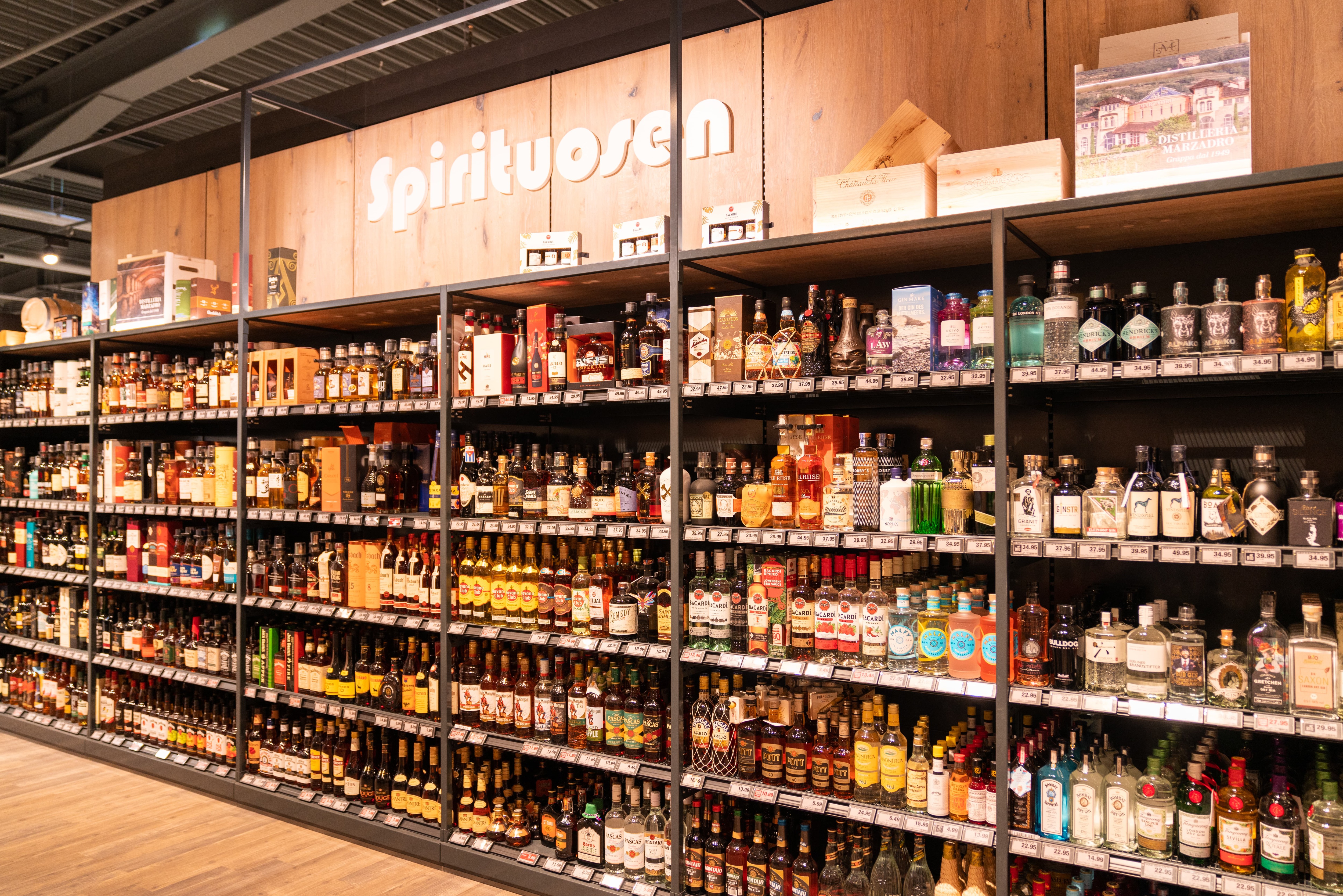 Spirituosenregal vor Holzvertäfelung in einem Supermarkt.