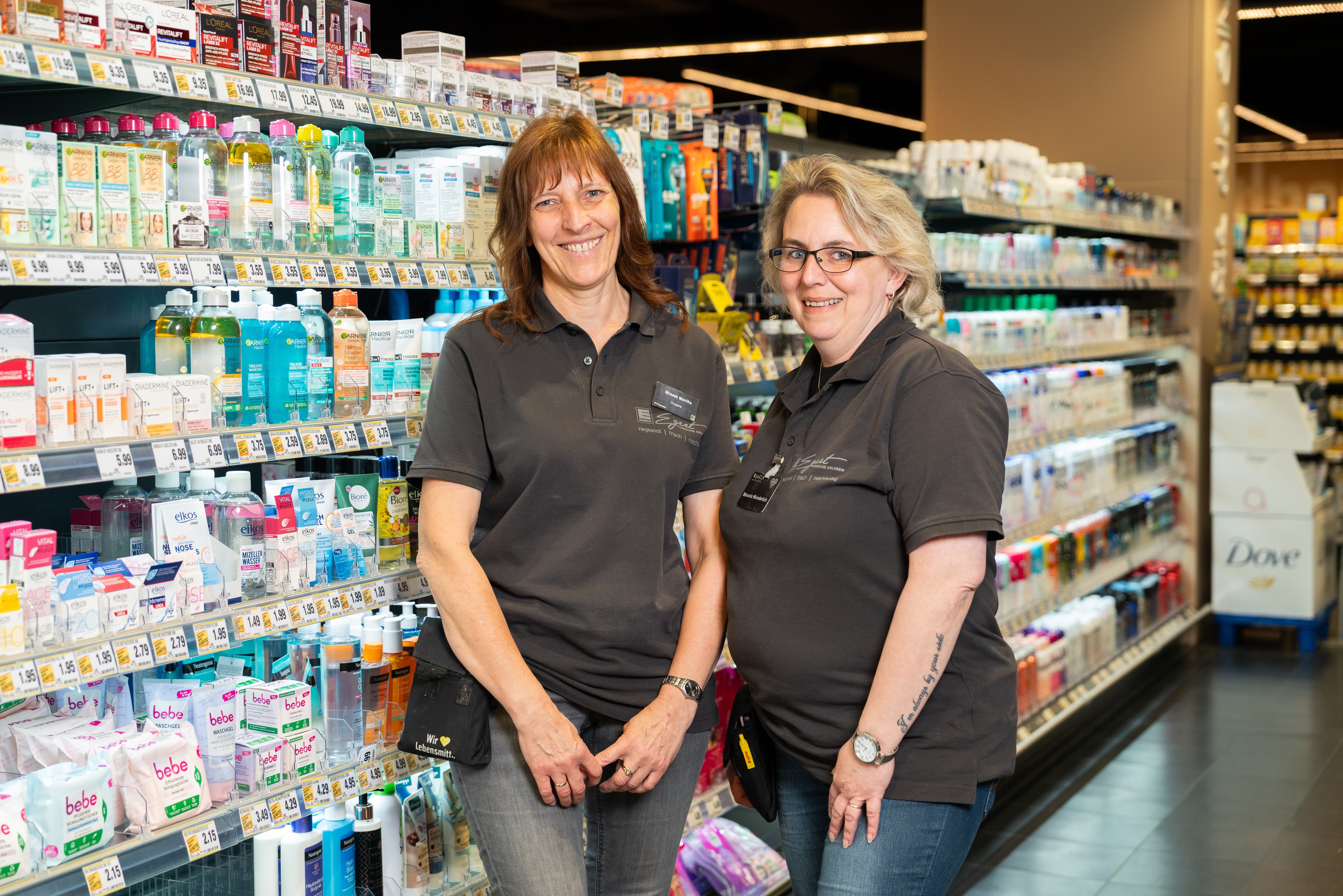 Zwei lächelnde Mitarbeiterinnen in der Hygieneabteilung eines EDEKA-Marktes.