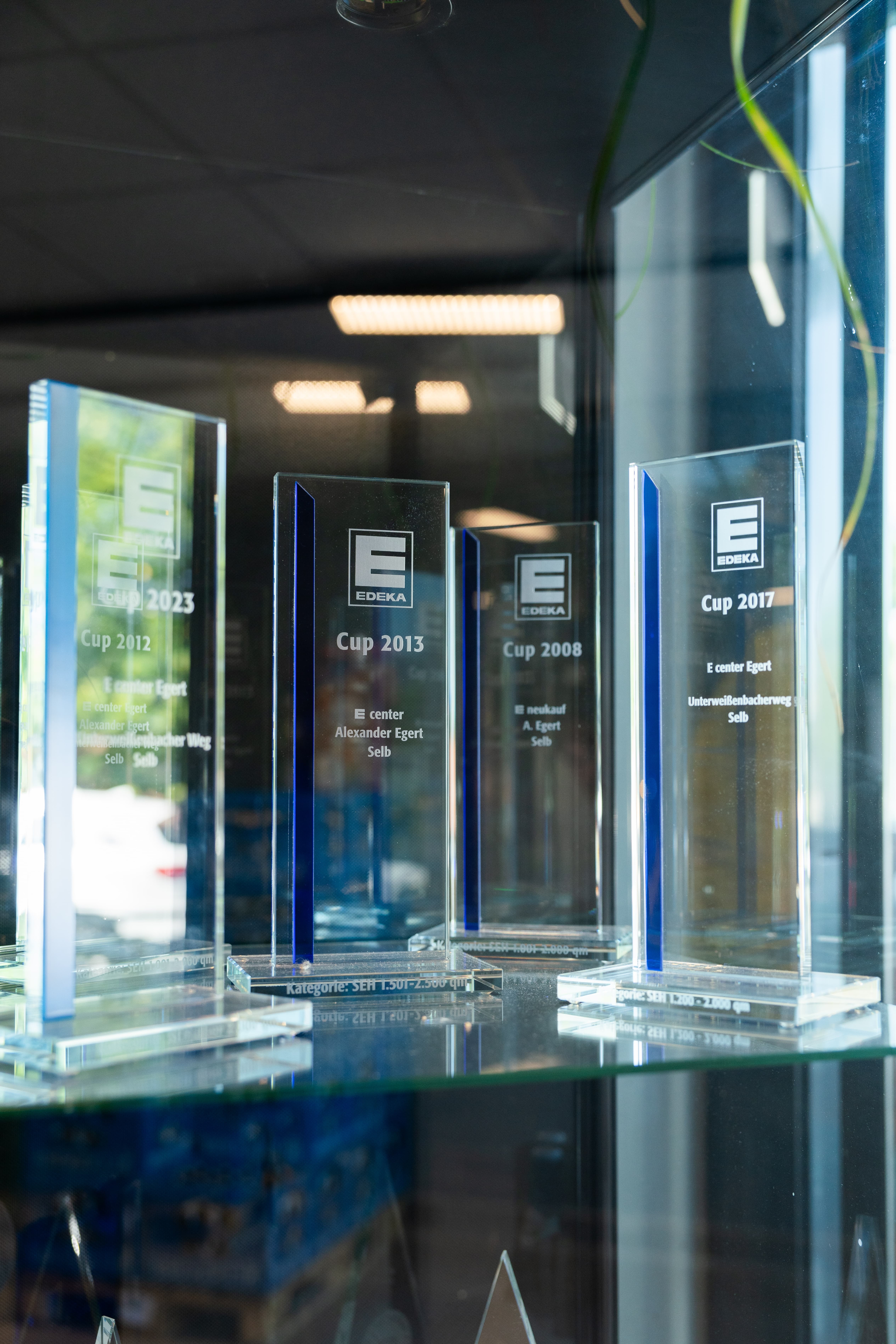 Vier gläserne Trophäen für den Gewinn des "EDEKA Cups" in unterschiedlichen Jahren.